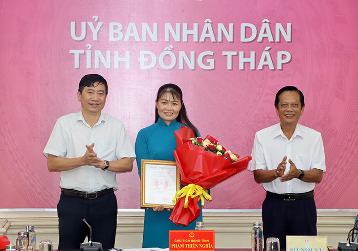 Chủ tịch UBND tỉnh Đồng Tháp Phạm Thiện Nghĩa (trái) trao quyết định và tặng hoa chúc mừng bà Phạm Thị Ngọc Đào. Ảnh: V. Tiến.
