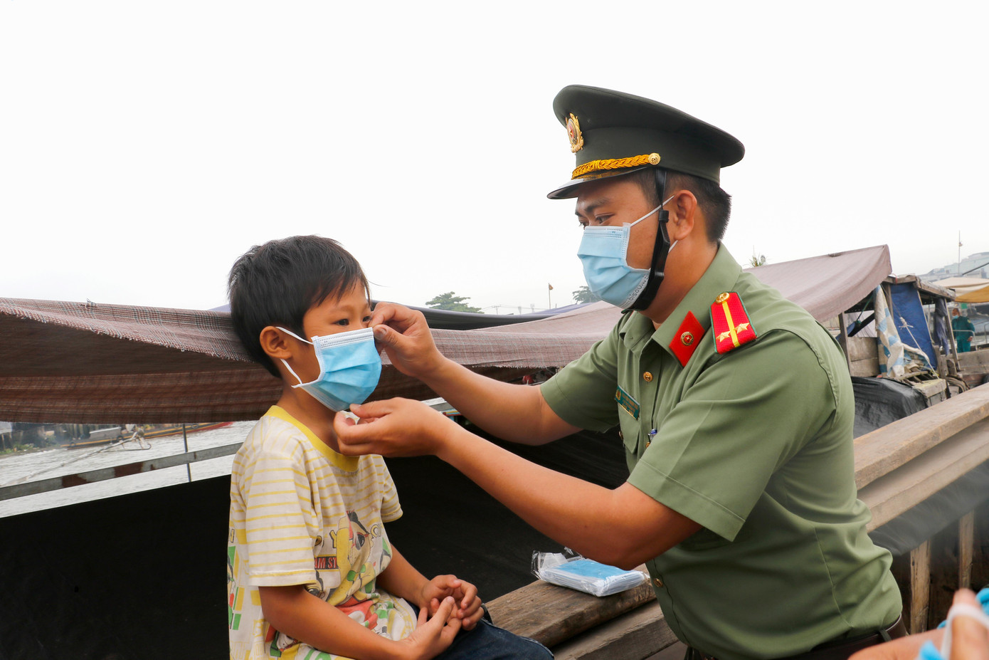 Chiến sĩ công an đeo khẩu trang cho trẻ em ở chợ nổi Cái Răng