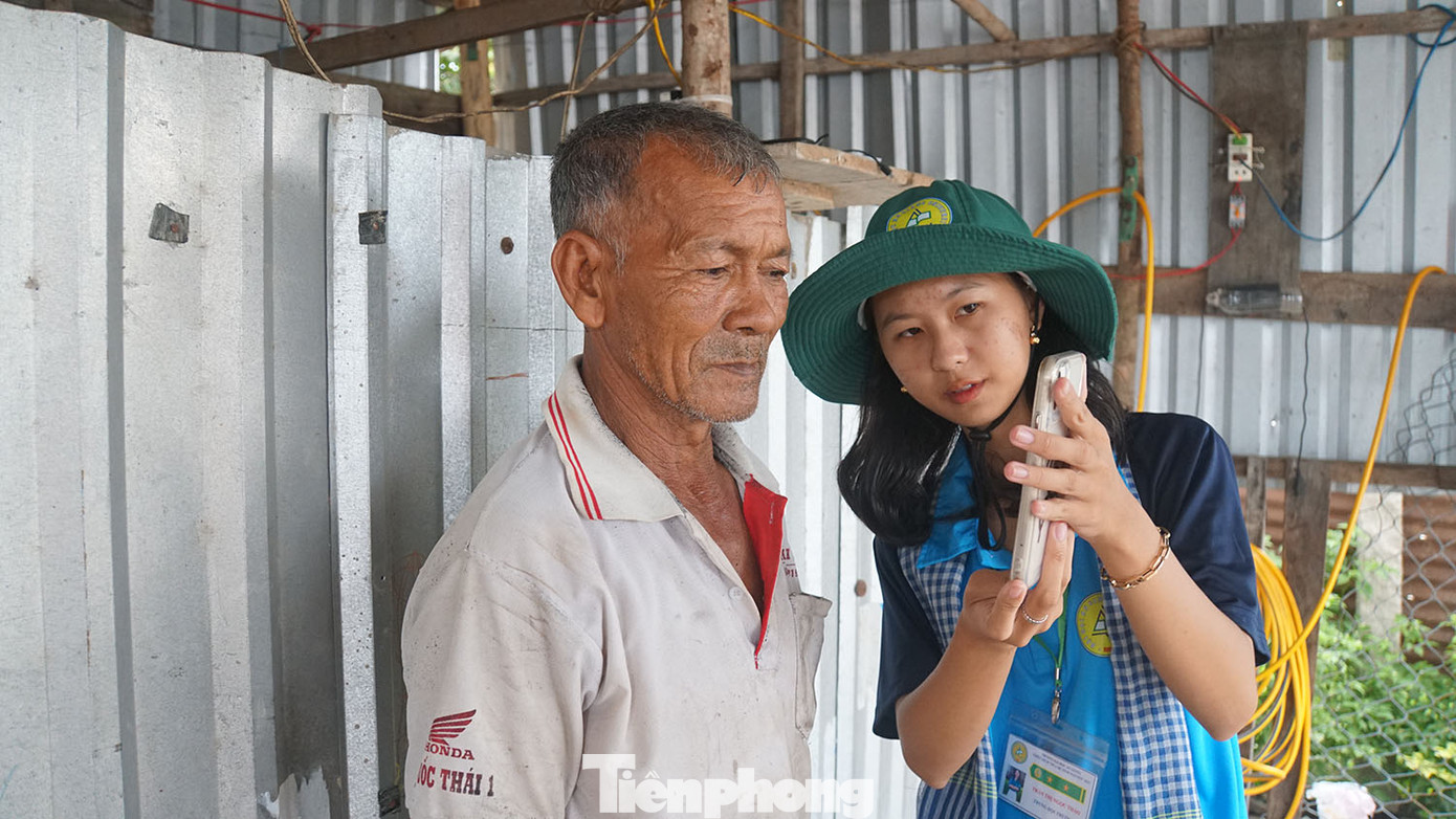 Chiến sĩ tình nguyện trường đại học An Giang hỗ trợ người dân cài đặt ứng dụng VNeID. Ảnh: Hòa Hội.
