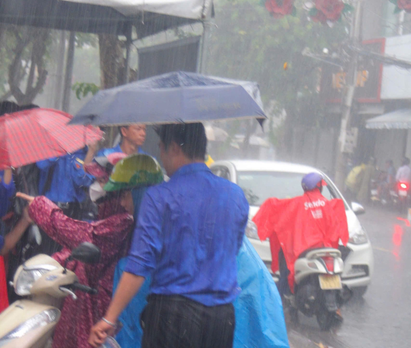 Tình nguyện viên dầm mưa hỗ trợ thí sinh tại TP. Sa Đéc, tỉnh Đồng Tháp.