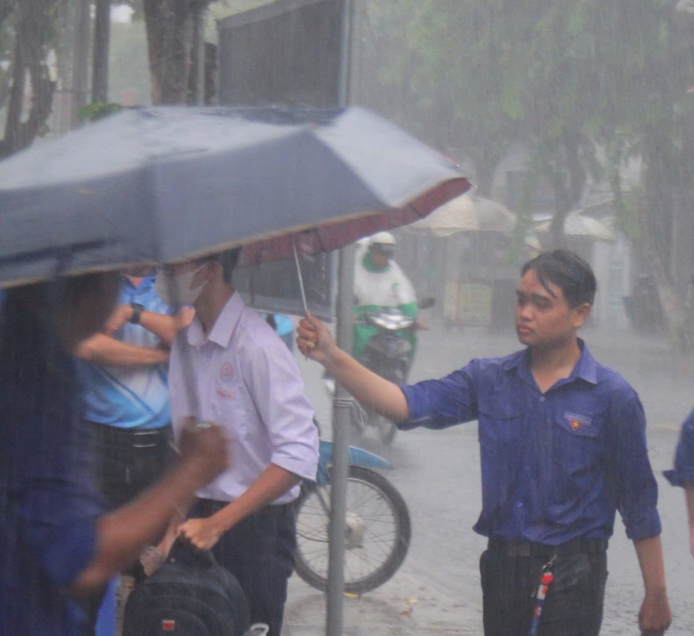 Tình nguyện viên dầm mưa hỗ trợ thí sinh tại Đồng Tháp.