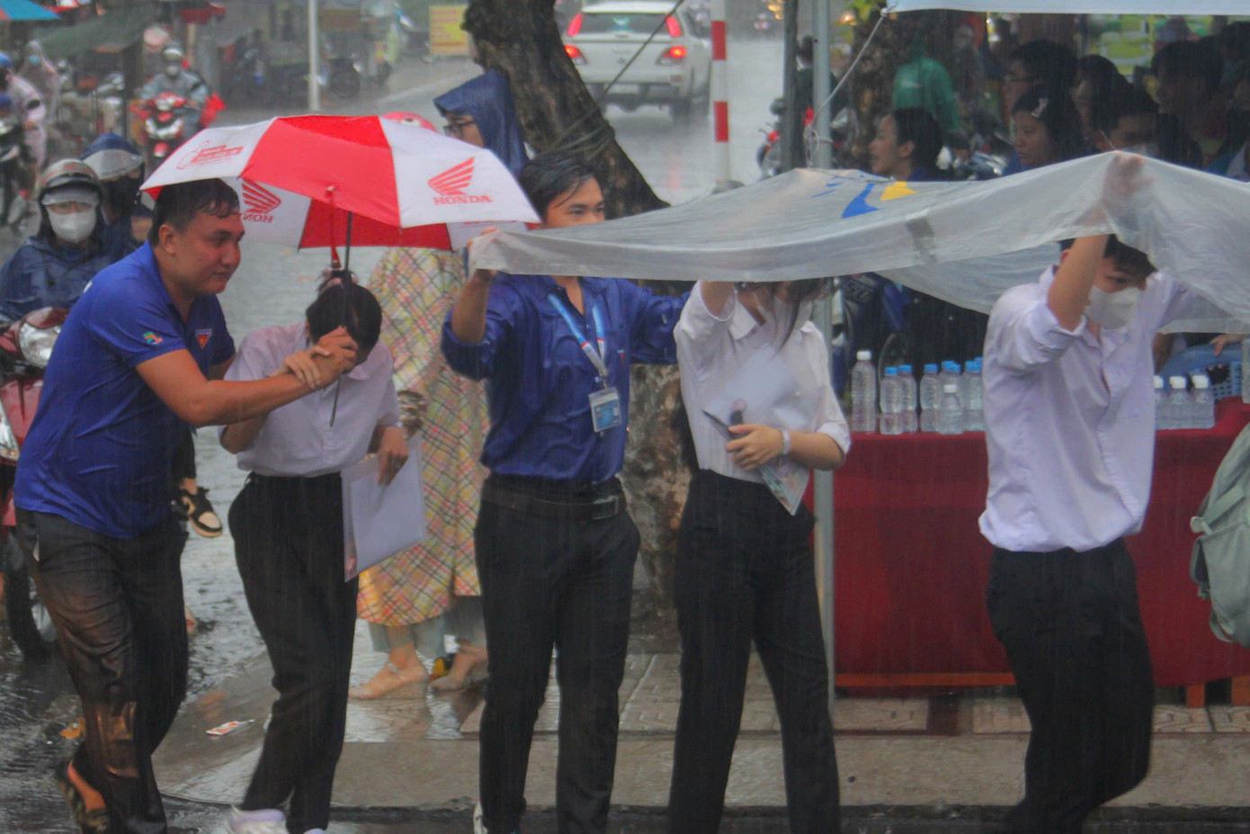 Thanh niên tình nguyện hỗ trợ che mưa cho thí sinh tại TP. Sa Đéc (Đồng Tháp) vào sáng nay.