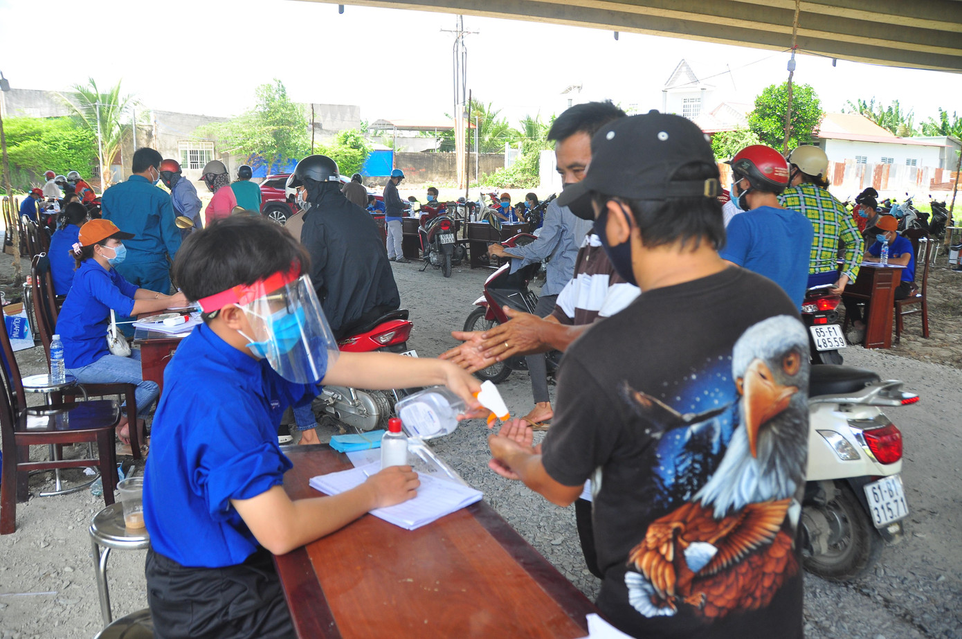 Tình nguyện viên xịt khử khuẩn cho người dân. - Ảnh: Hòa Hội