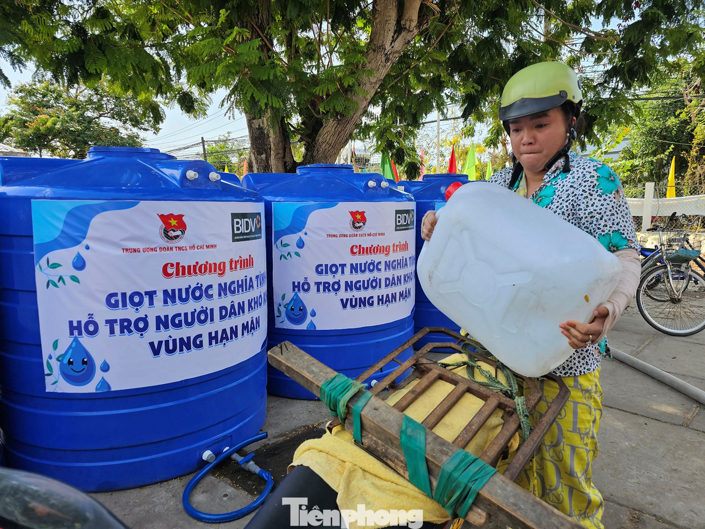 Người phụ nữ bê can nước lên xe gắn máy chở về nhà. Ảnh: Hòa Hội Người phụ nữ bê can nước lên xe gắn máy chở về nhà. Ảnh: Hòa Hội