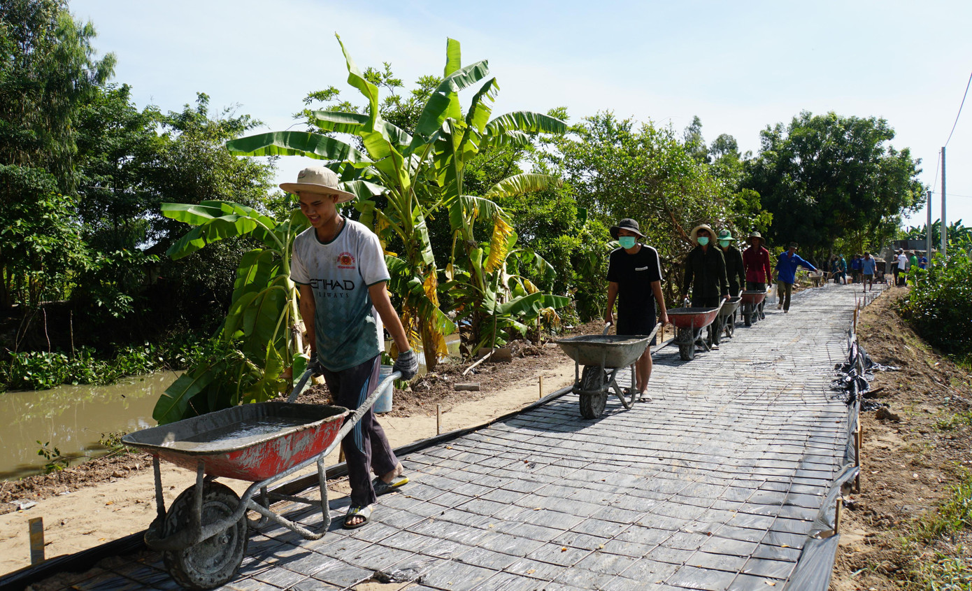 Giữa trưa nắng, hàng chục chiến sĩ cùng người dân làm việc hối hả trên công trình lộ giao thông nông thôn tại ấp Quy Lân 6, xã Thạnh Quới, huyện Vĩnh Thạnh, TP Cần Thơ. - Ảnh: Hòa Hội