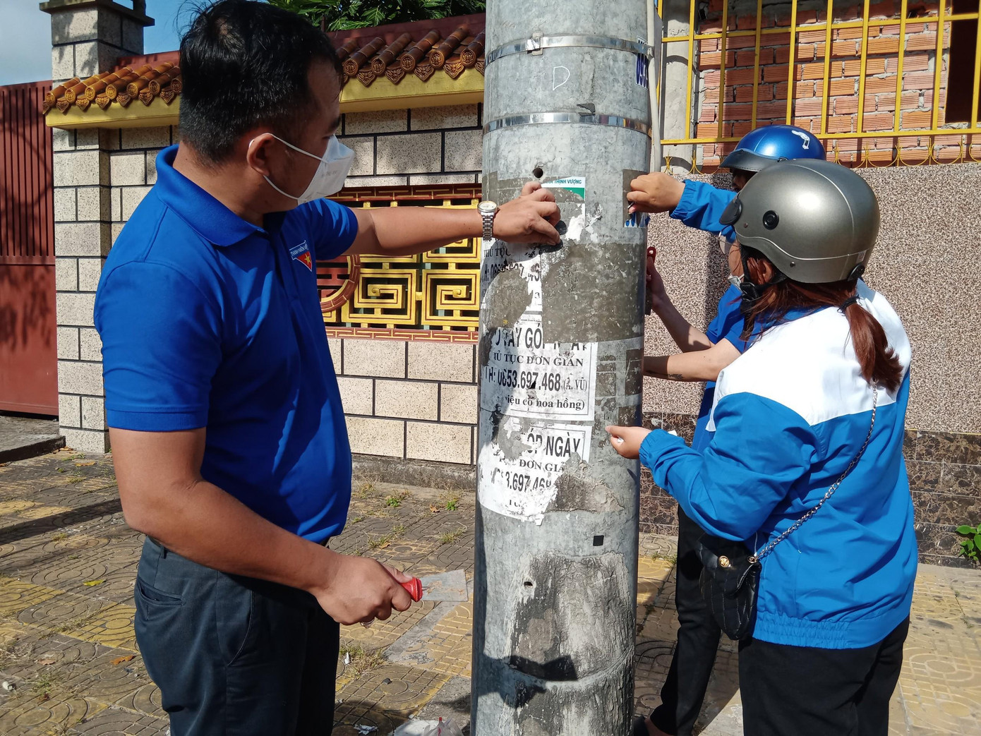 Đoàn viên thanh niên xóa tờ rơi quảng cáo trên cột điện.