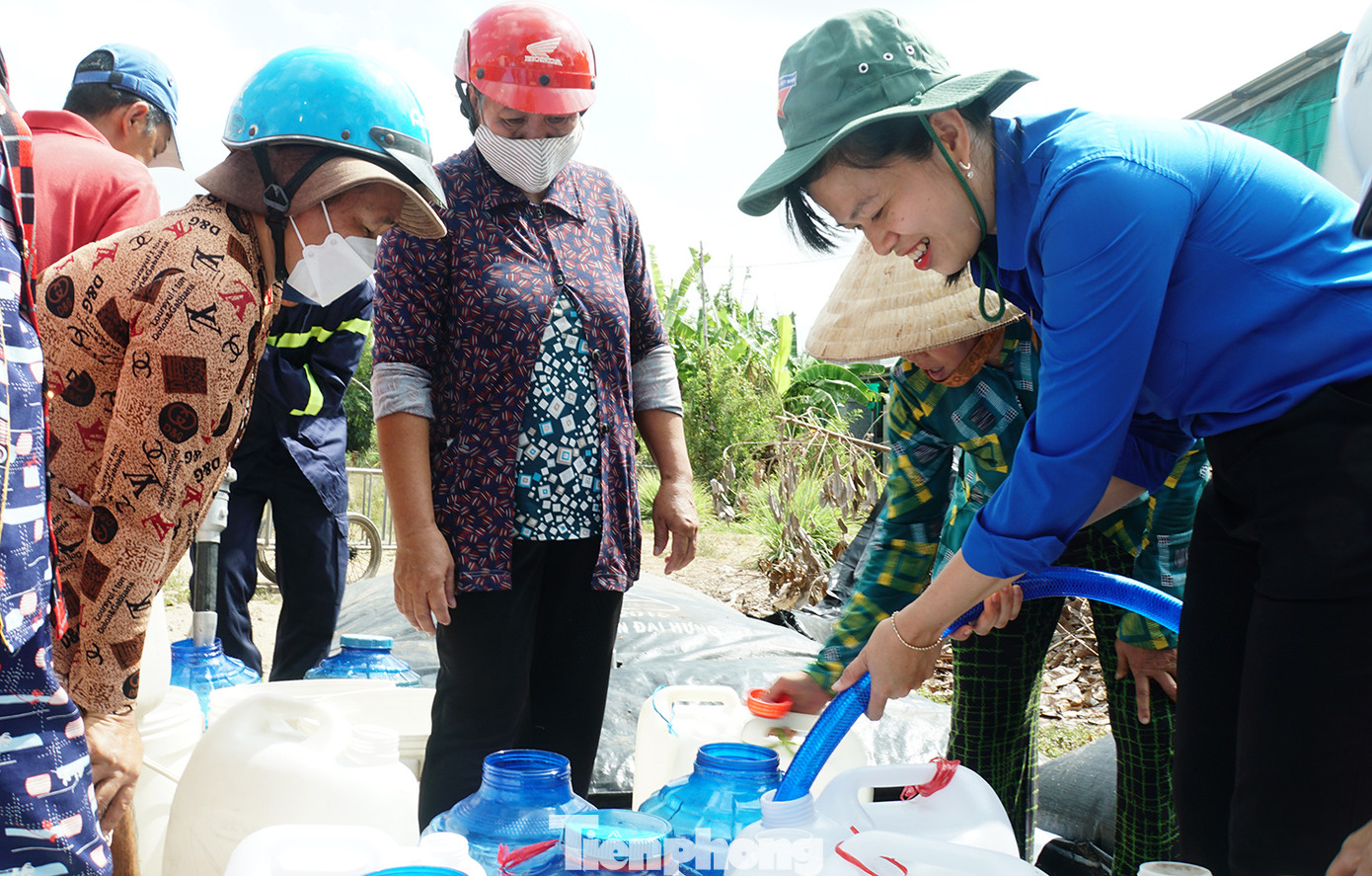 Nữ cán bộ Đoàn Bến Tre nở nụ cười hỗ trợ nước cho bà con giữa trưa nắng. Ảnh: Hòa Hội
