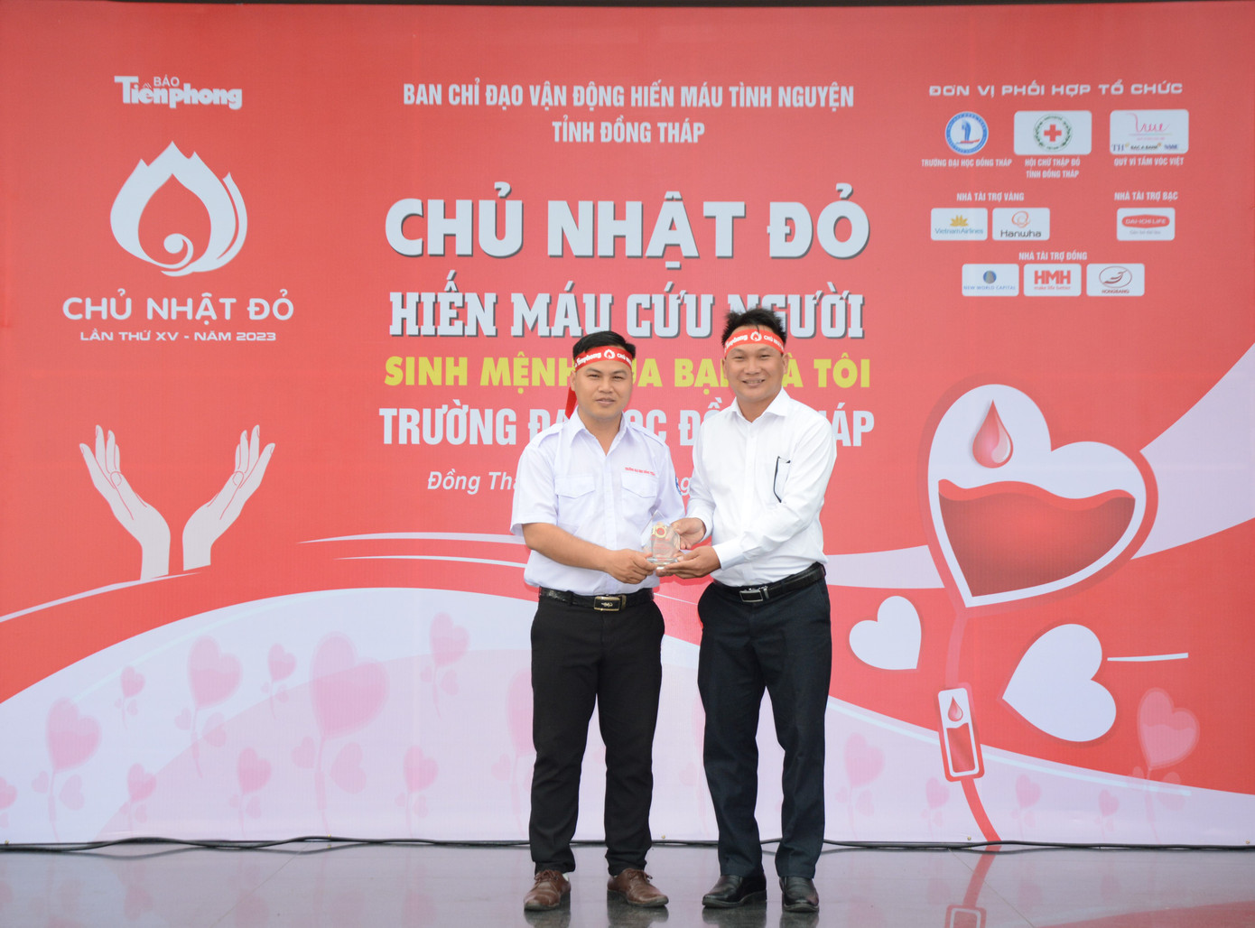Đại diện báo Tiền Phong (bên phải) trao tặng Kỷ niệm chương đồng hành tổ chức Chủ nhật Đỏ cho Đoàn trường đại học Đồng Tháp.