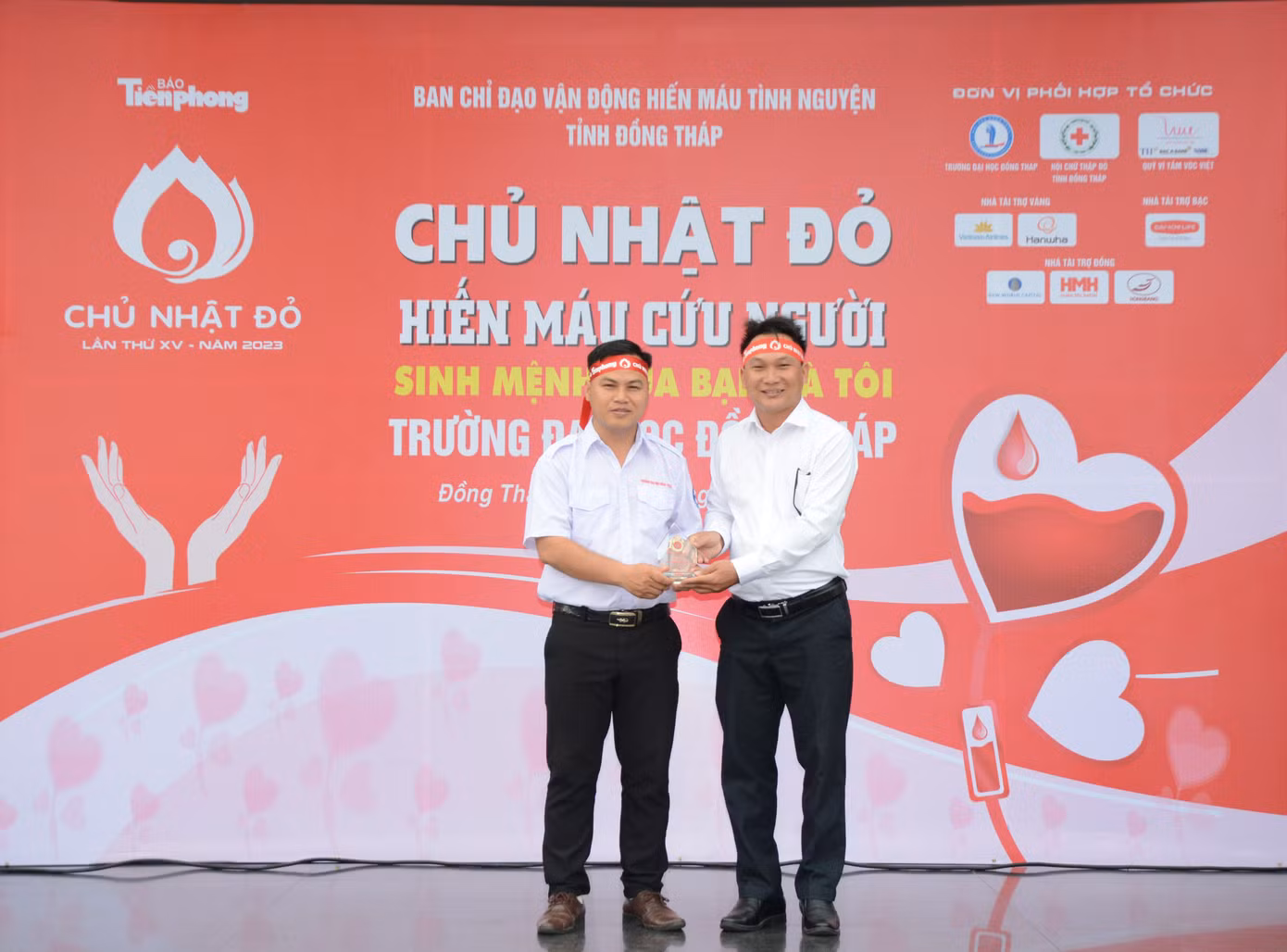Đại diện báo Tiền Phong (bên phải) trao tặng Kỷ niệm chương đồng hành tổ chức Chủ nhật Đỏ cho Đoàn trường đại học Đồng Tháp.