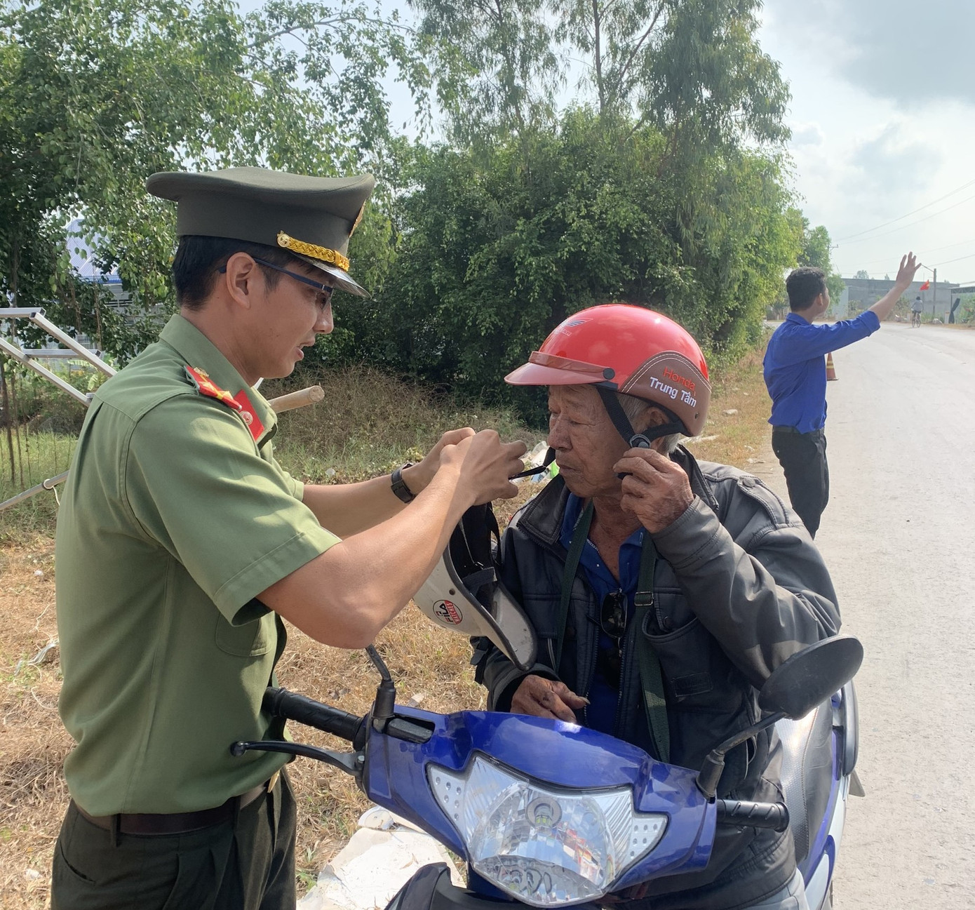 Chiến sĩ công an tặng nón bảo hiểm cho người dân.