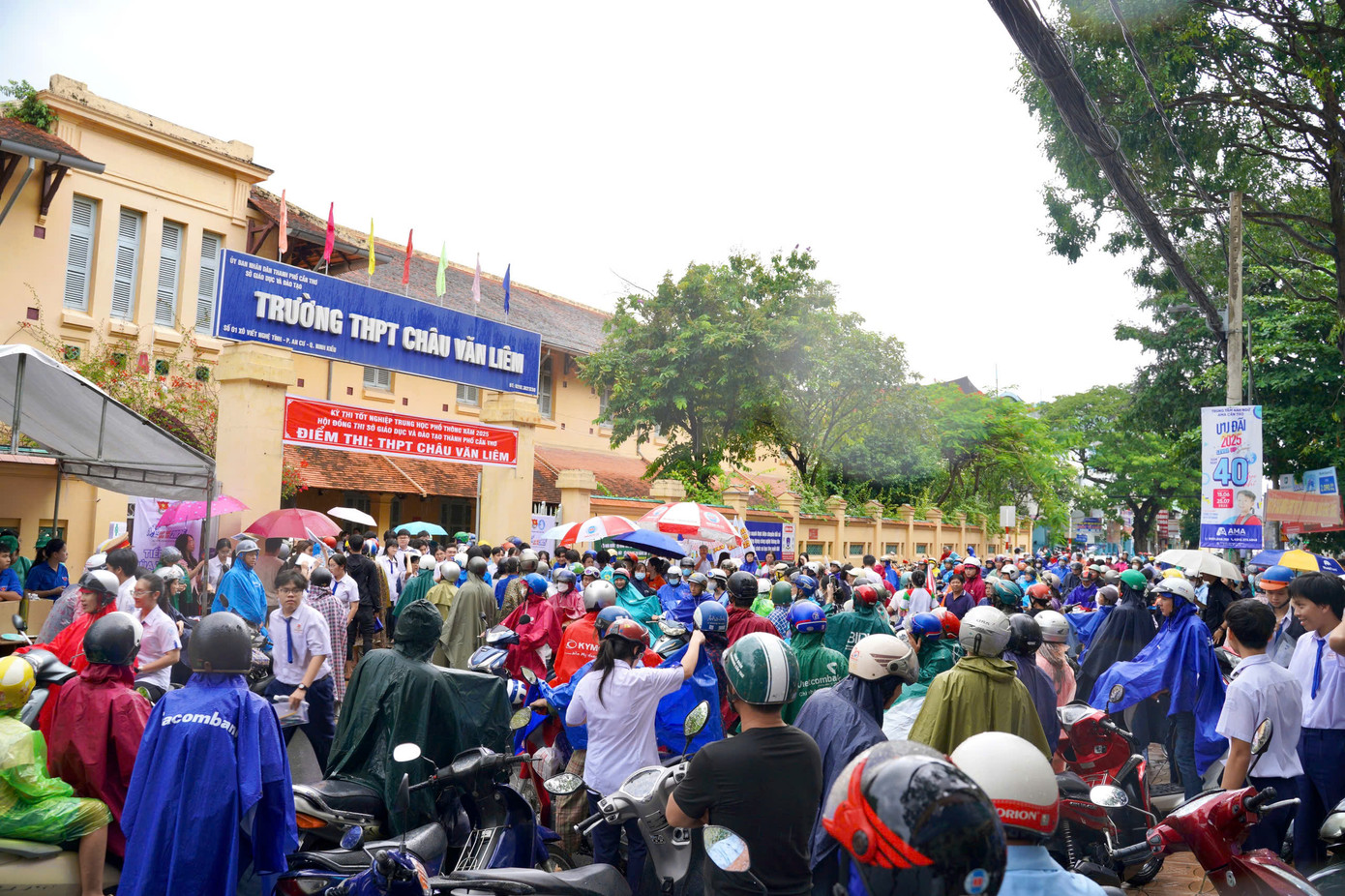 Phụ huynh mặc áo mưa đón con tại điểm thi trường THPT Châu Văn Liêm, TP. Cần Thơ.