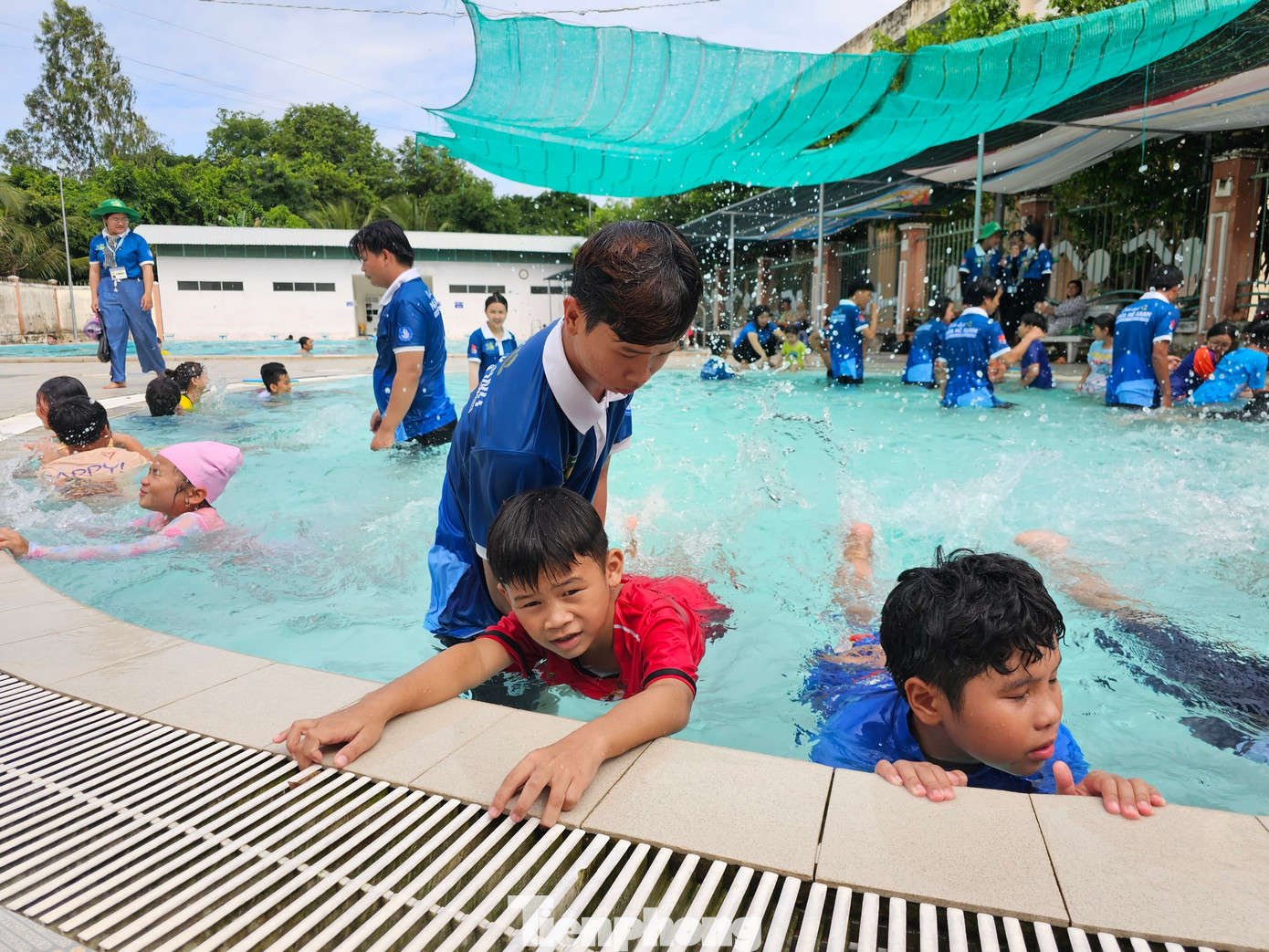 Tình nguyện viên hướng dẫn các em bơi. Ảnh: Hòa Hội