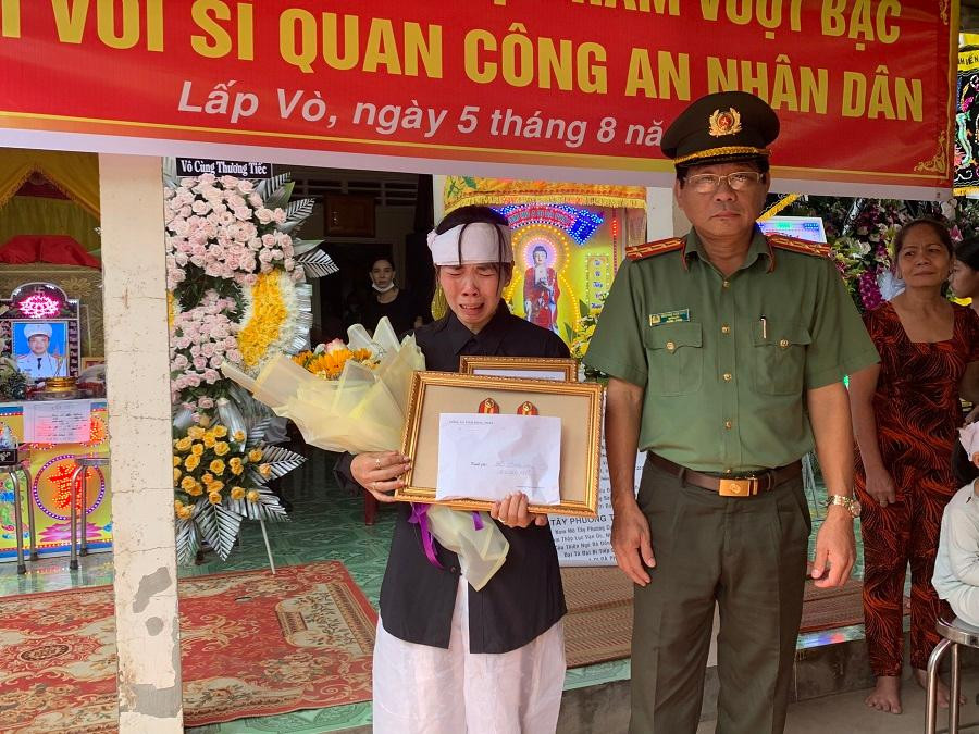 Đại tá Nguyễn Văn Hiểu - Giám đốc Công an tỉnh Đồng Tháp trao quyết định thăng cấp bậc hàm cho đồng chí Dương (vợ đồng chí Dương nhận). - Ảnh: CA ĐT