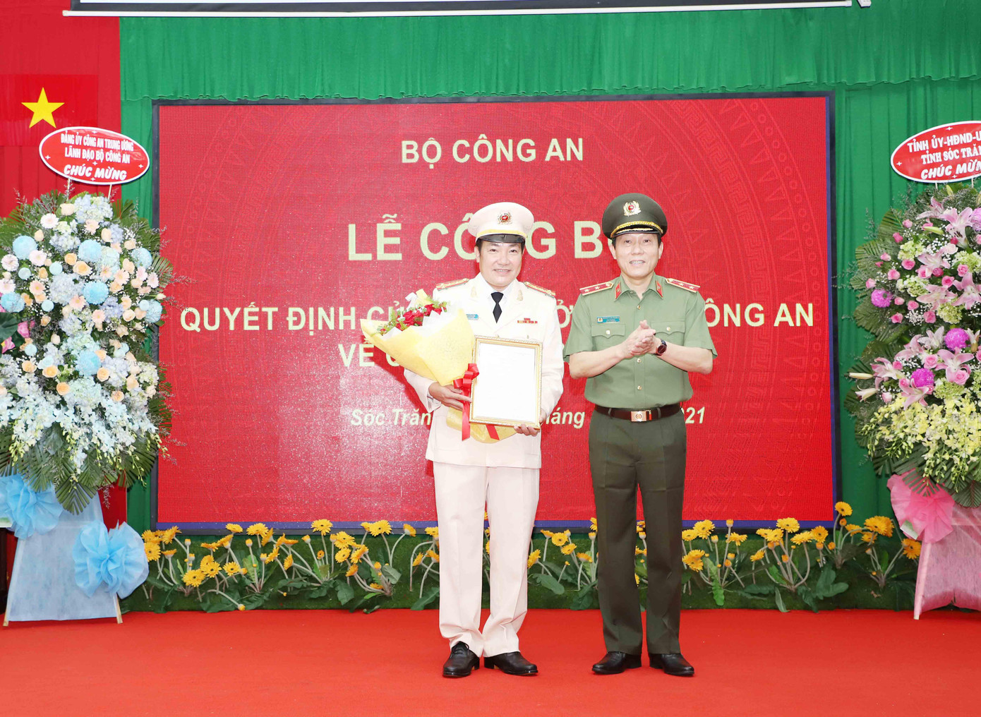 Thứ trưởng Bộ công an Lương Tam Quang (bên phải) trao Quyết định và tặng hoa chúc mừng Đại tá Lâm Thành Sol.