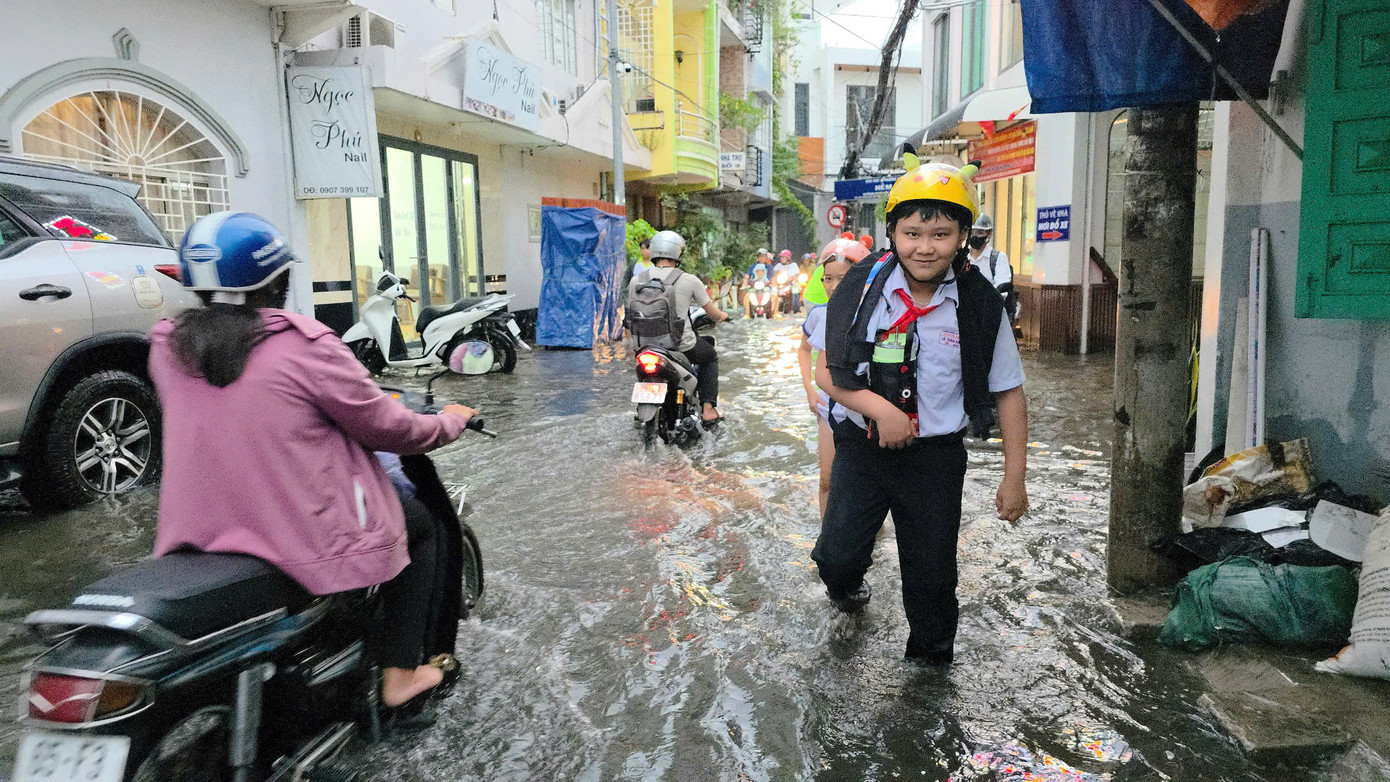 Cơn mưa to cùng thời điểm tan học và tan giờ làm khiến người dân và các em học sinh phải lội nước về nhà.