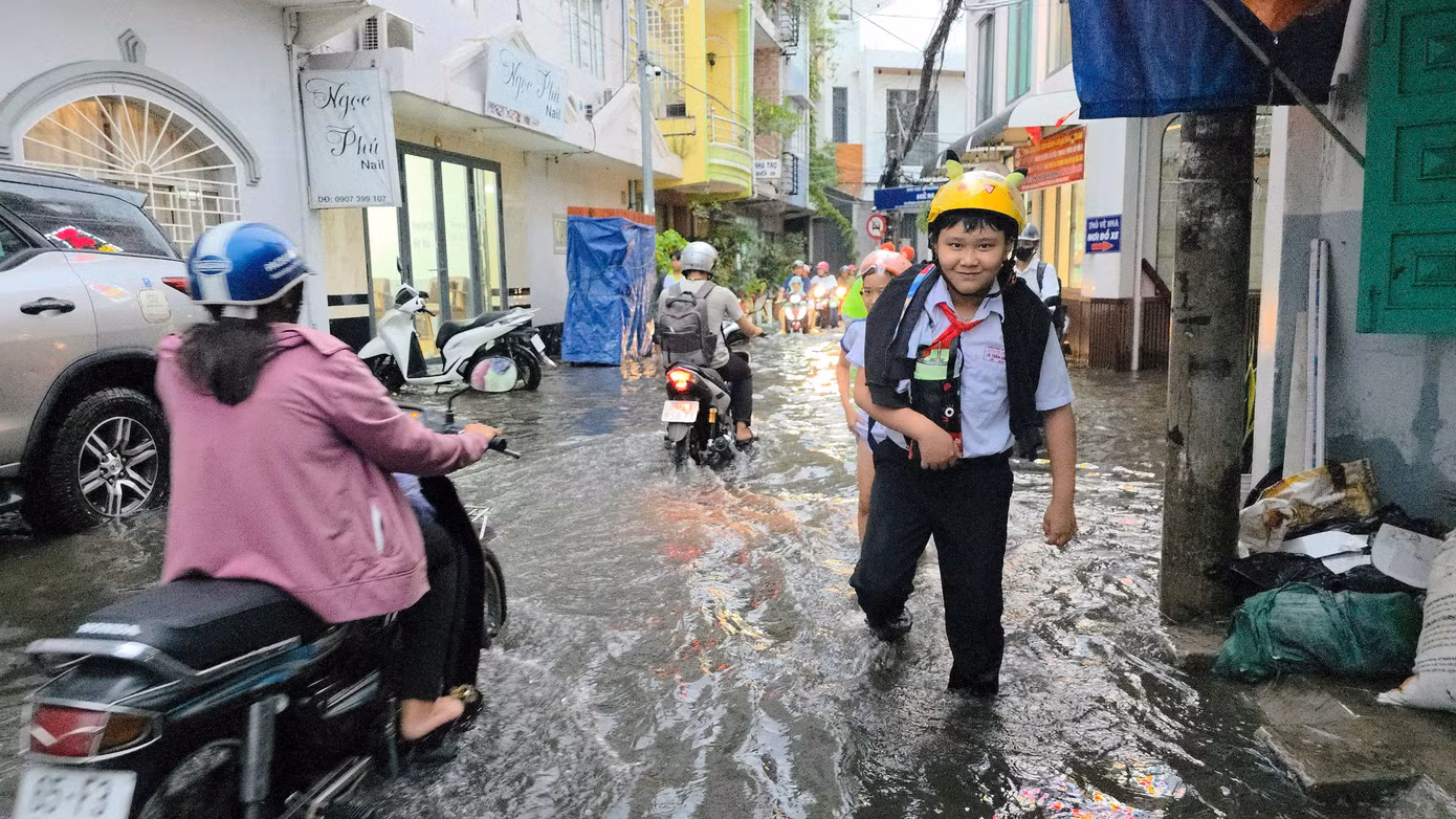 Cơn mưa to cùng thời điểm tan học và tan giờ làm khiến người dân và các em học sinh phải lội nước về nhà.