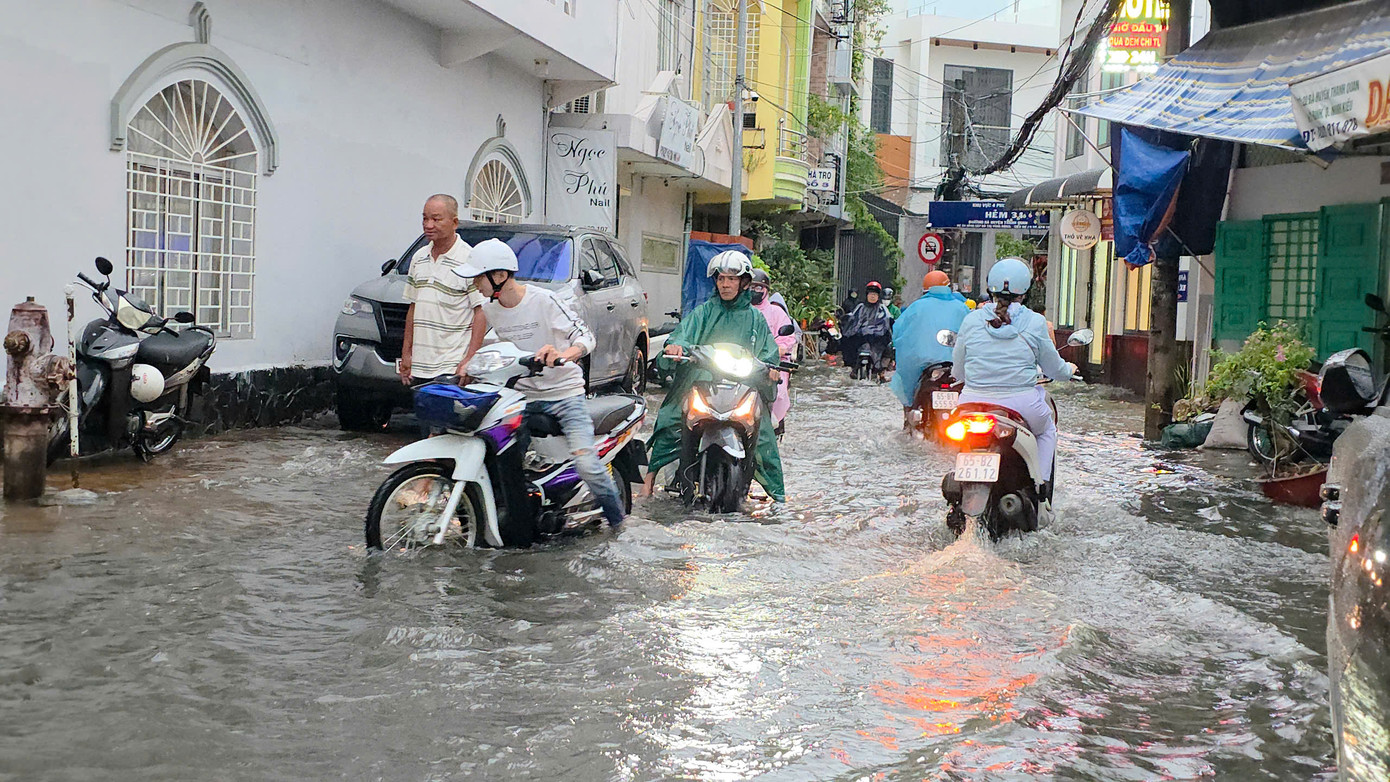 Người dân vất vả trên đường do ngập nước.