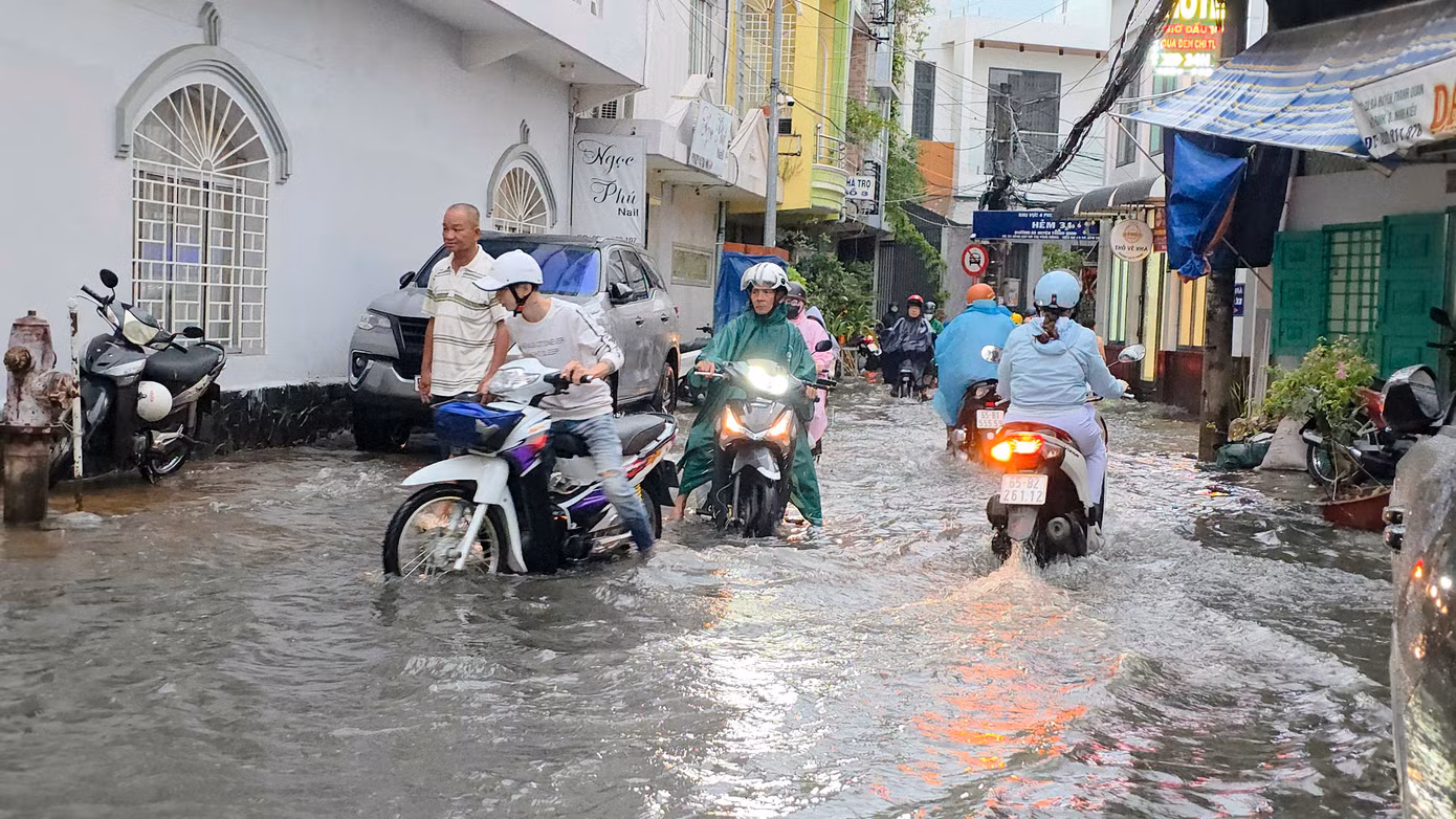 Người dân vất vả trên đường do ngập nước.