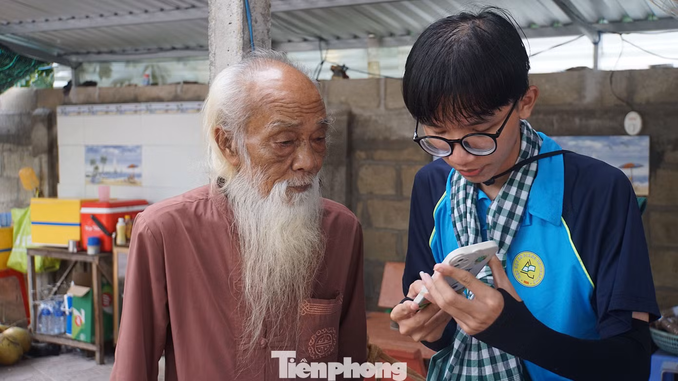 Chiến sĩ tình nguyện Trường đại học An Giang giúp cụ già cài đặt ứng dụng VNeID.