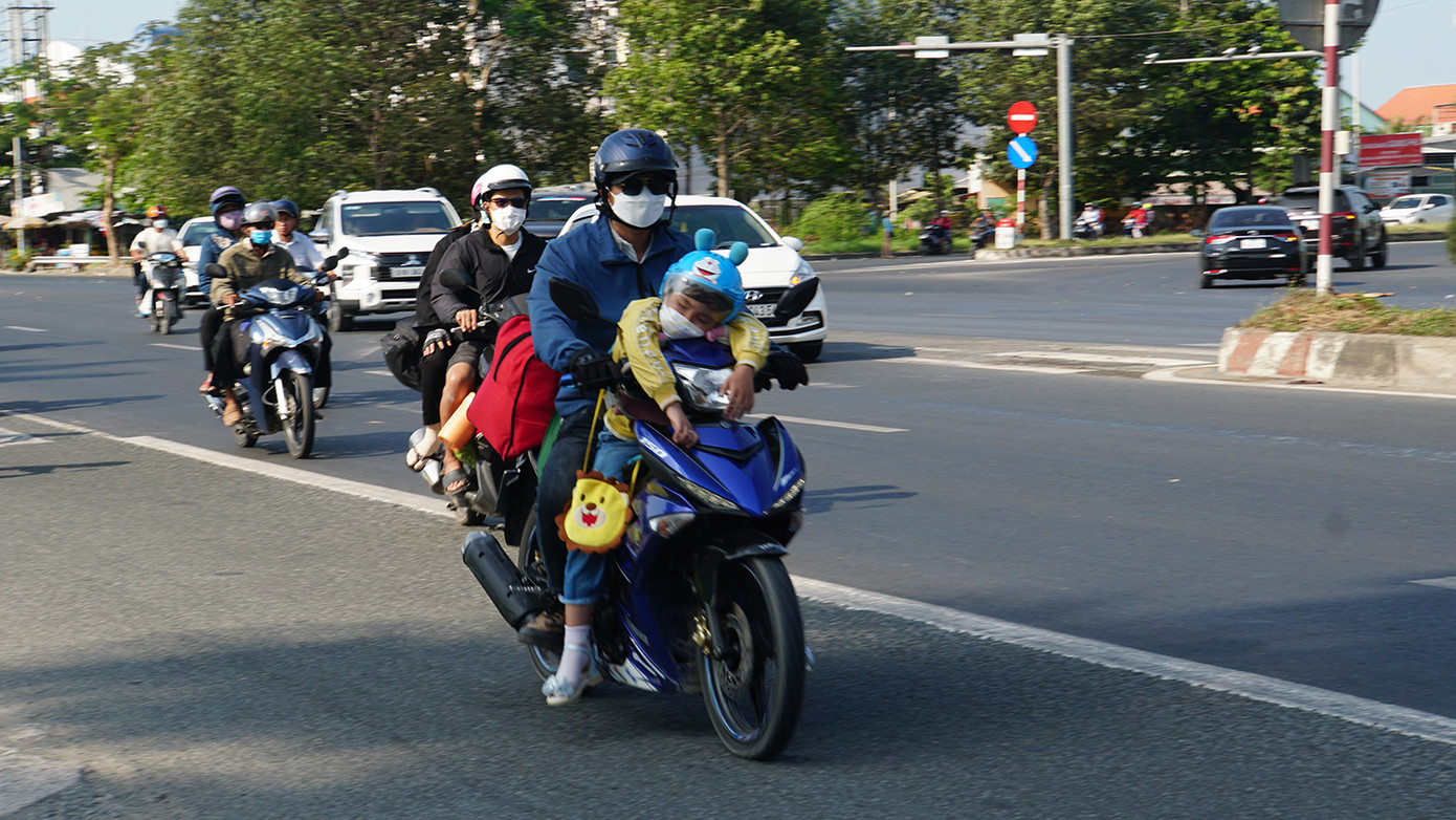 Trẻ em mệt mỏi ngủ trên xe gắn máy. Ảnh: Hòa Hội