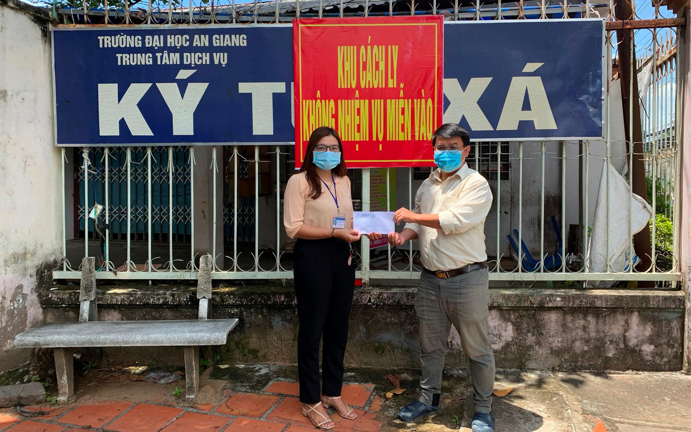 Anh Trần Trung Quốc trao tiền hỗ trợ của các bạn tình nguyện viên cho đại diện Ban quản lý khu cách ly trường ĐH An Giang.