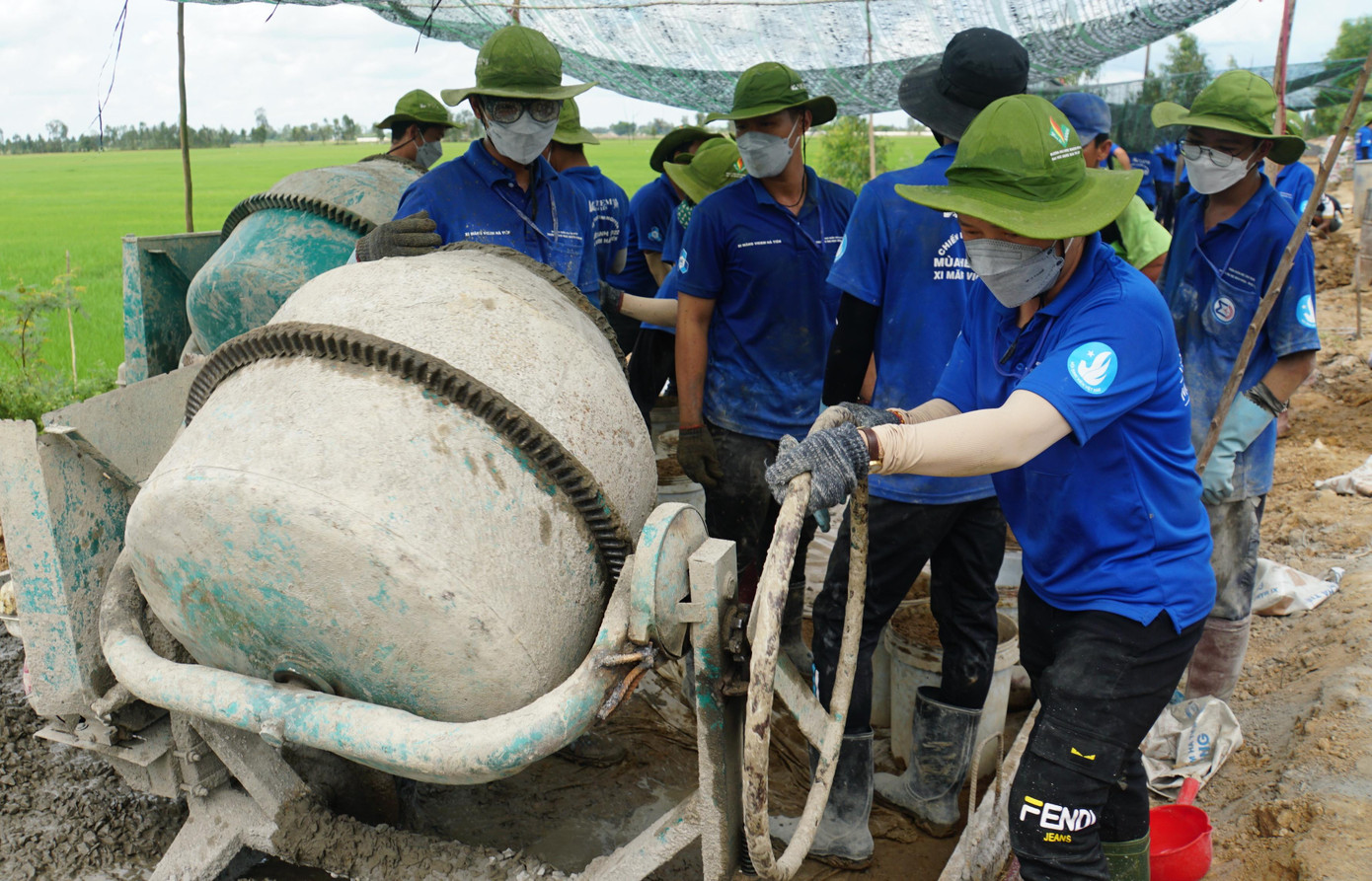 Chỉ huy trưởng là cô Phan Thị Thanh Hương, Giảng viên bộ môn Lý luận Chính trị - Khoa Khoa học - ứng dụng (trường Đại học Bách khoa) là người đứng cối, chỉ huy cả đội làm; đồng thời, người đứng cối bên cạnh cũng là cô gái Nguyễn Thanh Hằng. “Ngày đầu làm rất nặng, vất vả; chưa kể đứng cối khói bụi của xi măng, cát đá bay khắp người nhưng tụi em cố gắng hoàn thành”, cô Hương chia sẻ. - Ảnh: Hòa Hội