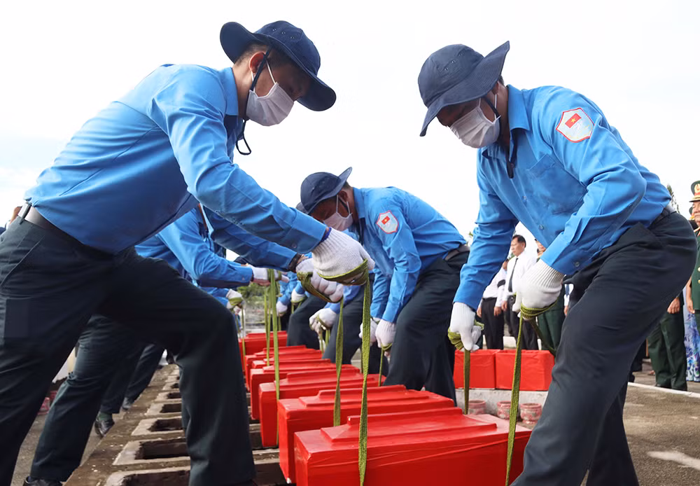 Thực hiện nghi thức an táng hài cốt liệt sĩ tại nghĩa trang liệt sĩ Dốc Bà Đắc. Ảnh: Gia Khánh.
