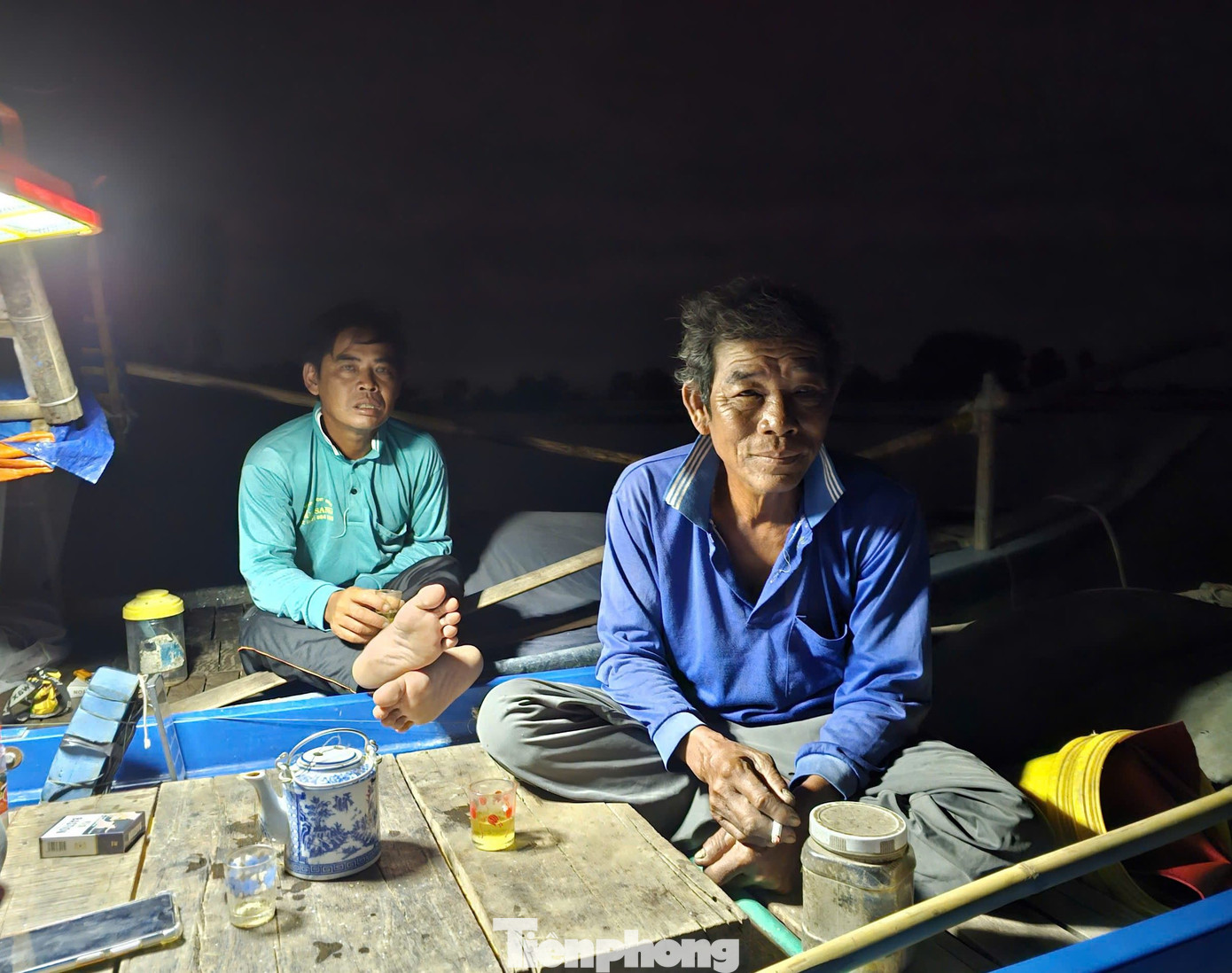 Hơn 2h sáng, ngày cuối tháng 10, ông Lê Văn Thảo (trái) ở xã Phú Hiệp, huyện Phú Tân, (An Giang) thức dậy chuẩn bị ra cánh đồng biên giới giăng lưới, thả câu. Ông Thảo cùng nhóm bạn giăng lưới, thả câu với 6 chiếc xuồng cặp nhau, cả nhóm thức dậy đốt lửa pha ấm trà, bàn chuyện cá mắm. Ảnh: Hòa Hội.
