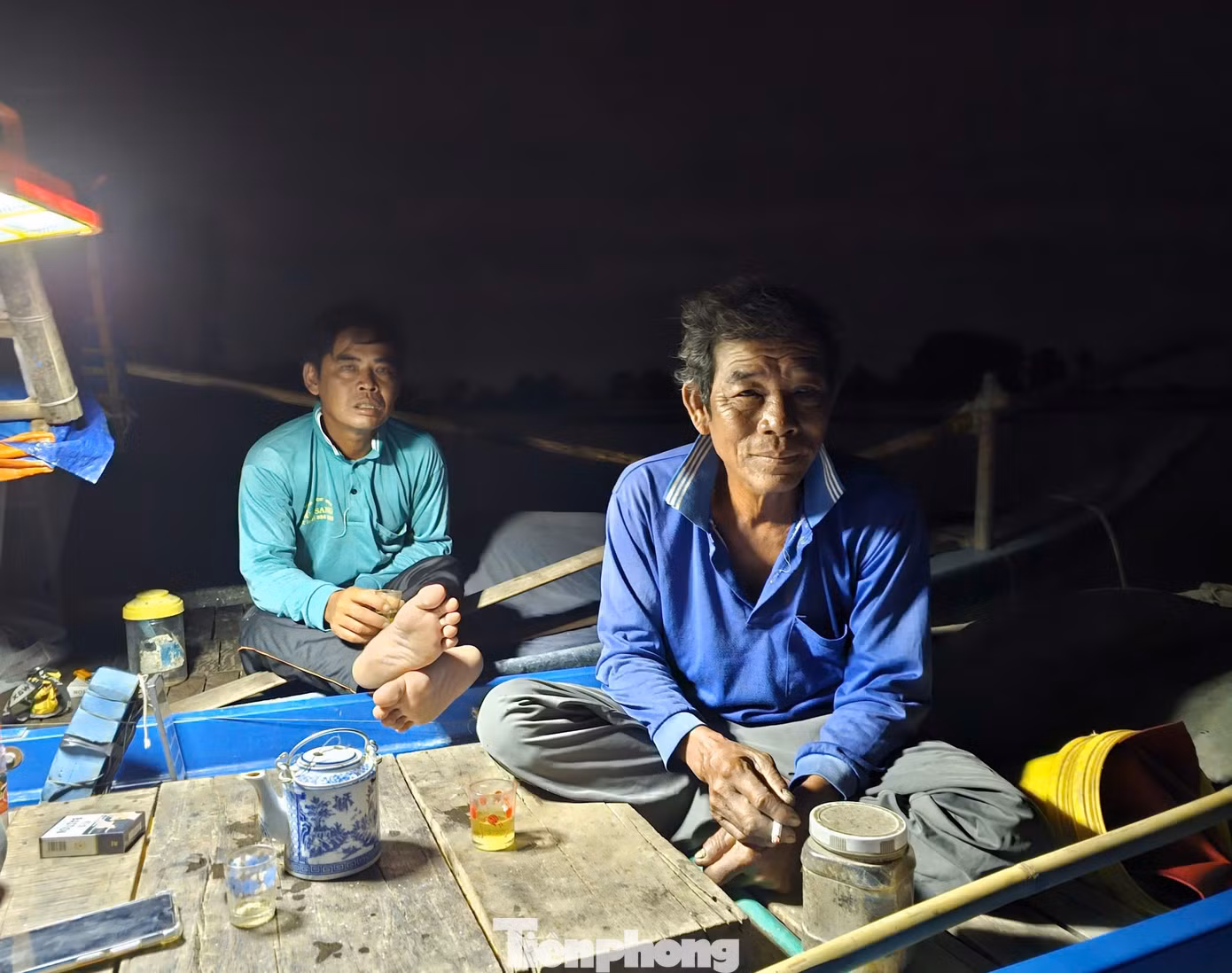 Hơn 2h sáng, ngày cuối tháng 10, ông Lê Văn Thảo (trái) ở xã Phú Hiệp, huyện Phú Tân, (An Giang) thức dậy chuẩn bị ra cánh đồng biên giới giăng lưới, thả câu. Ông Thảo cùng nhóm bạn giăng lưới, thả câu với 6 chiếc xuồng cặp nhau, cả nhóm thức dậy đốt lửa pha ấm trà, bàn chuyện cá mắm. Ảnh: Hòa Hội.
