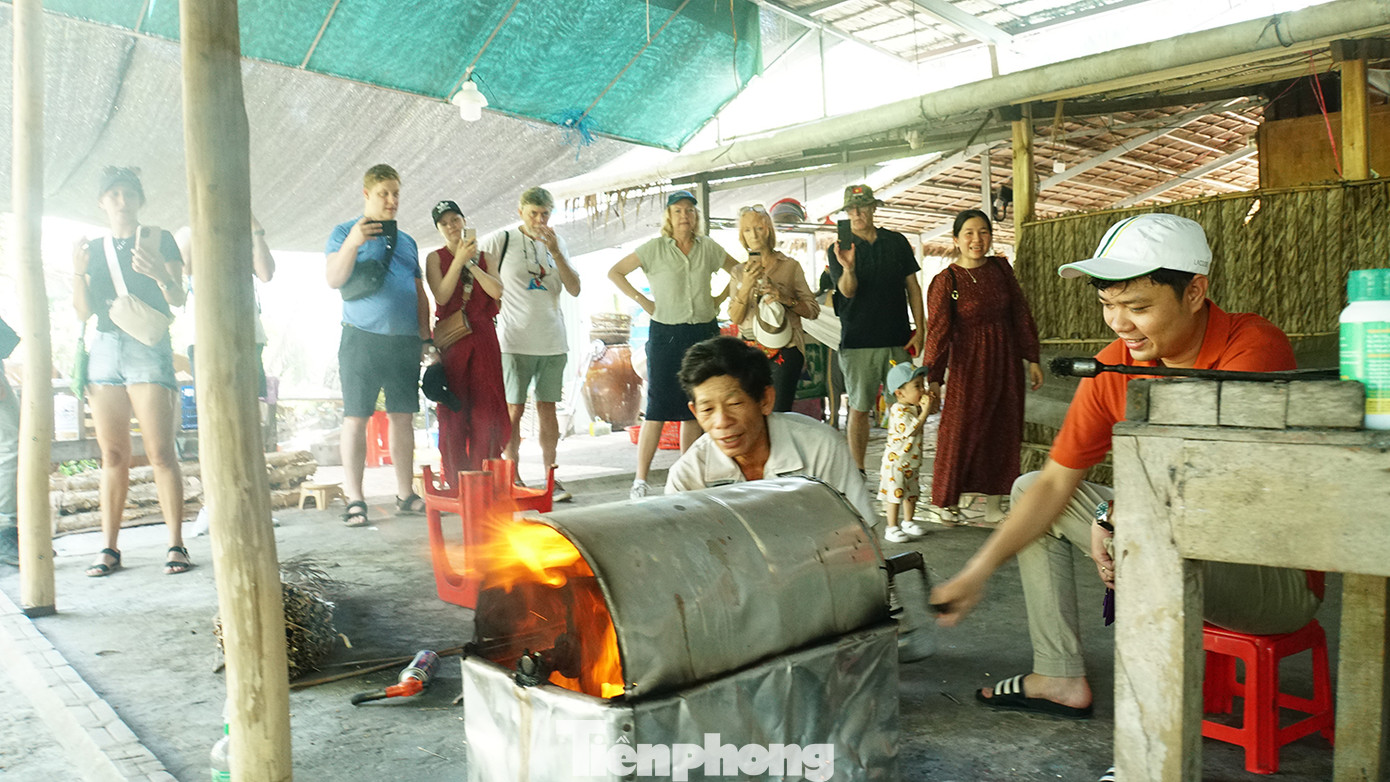 Khách trải nghiệm nổ cốm gạo tại nhà bà Bảy Muôn. Ảnh: Hòa Hội