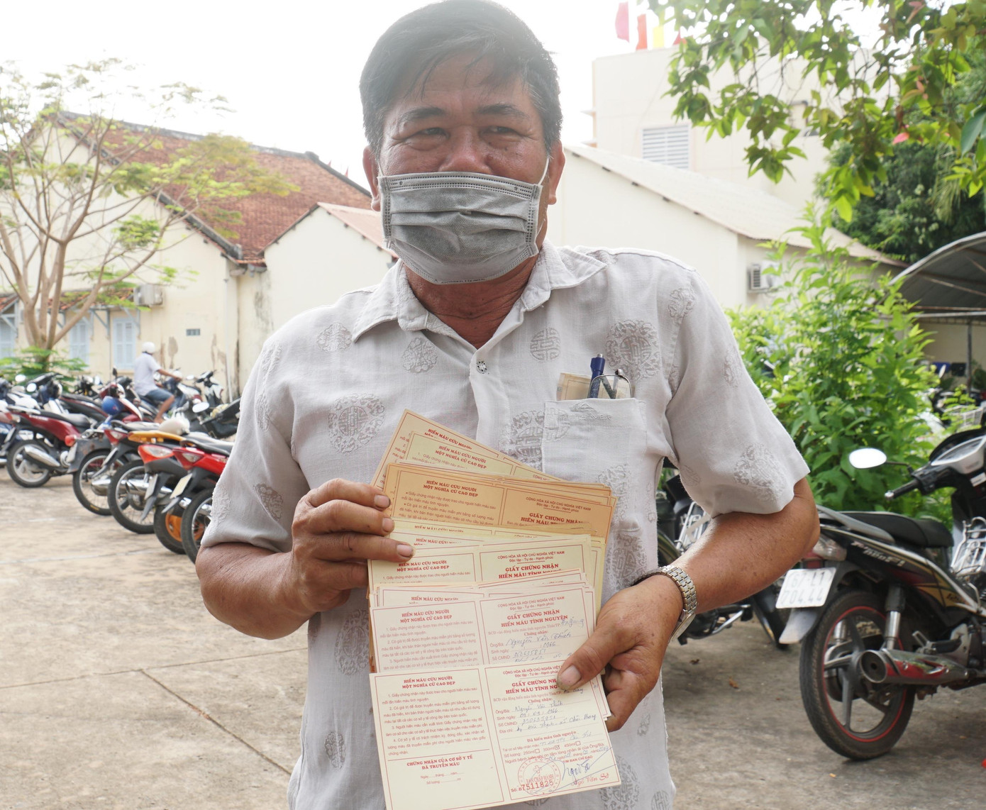 Ông Nguyễn Văn Thích cầm xấp chứng nhận hiến máu trên tay