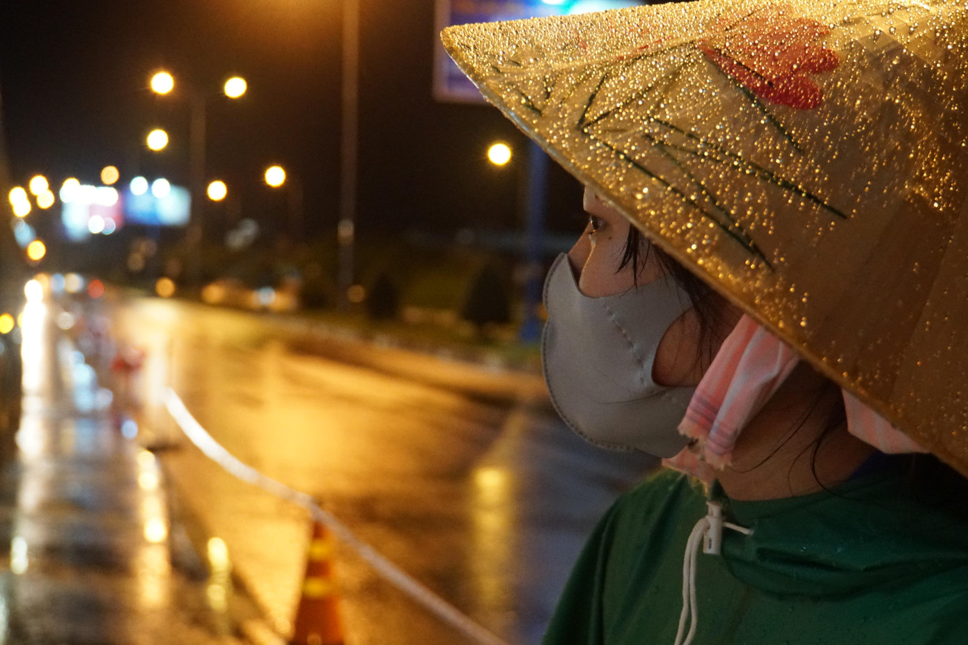 Nữ tình nguyện viên dầm mưa làm nhiệm vụ chống dịch. - Ảnh: Hòa Hội