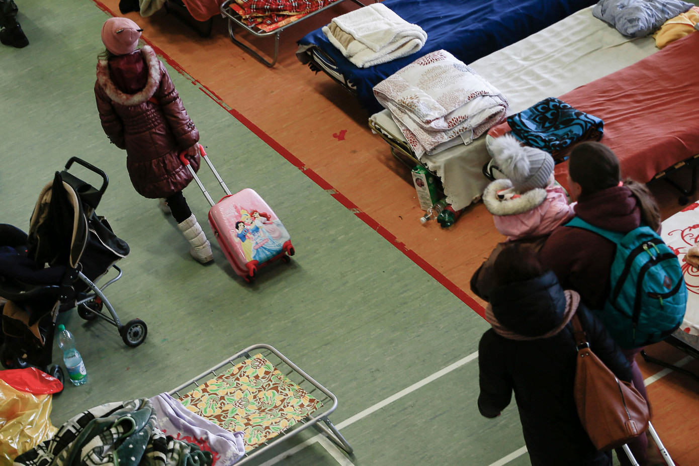 Một bé gái kéo vali đi giữa hàng trăm chiếc giường bên trong một nhà thi đấu thể thao được sử dụng để chứa người tị nạn Ukraine tại thị trấn biên giới Medyka, Ba Lan ngày 1/3. Ảnh: AP.