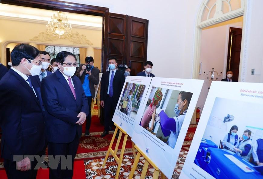 Thủ tướng Phạm Minh Chính tham quan trưng bày ảnh về hoạt động đối ngoại vắc xin phòng, chống dịch COVID-19. (Ảnh: Dương Giang/TTXVN)