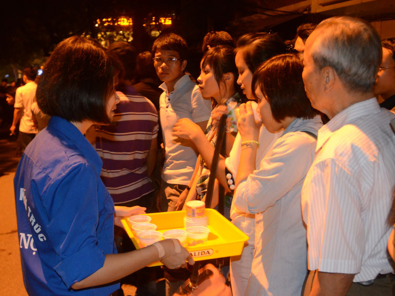 Tình nguyện viên mời người dân uống nước trong khi xếp hàng chờ viếng. Ảnh: Tiền Phong. Tình nguyện viên mời người dân uống nước trong khi xếp hàng chờ viếng. Ảnh: Tiền Phong