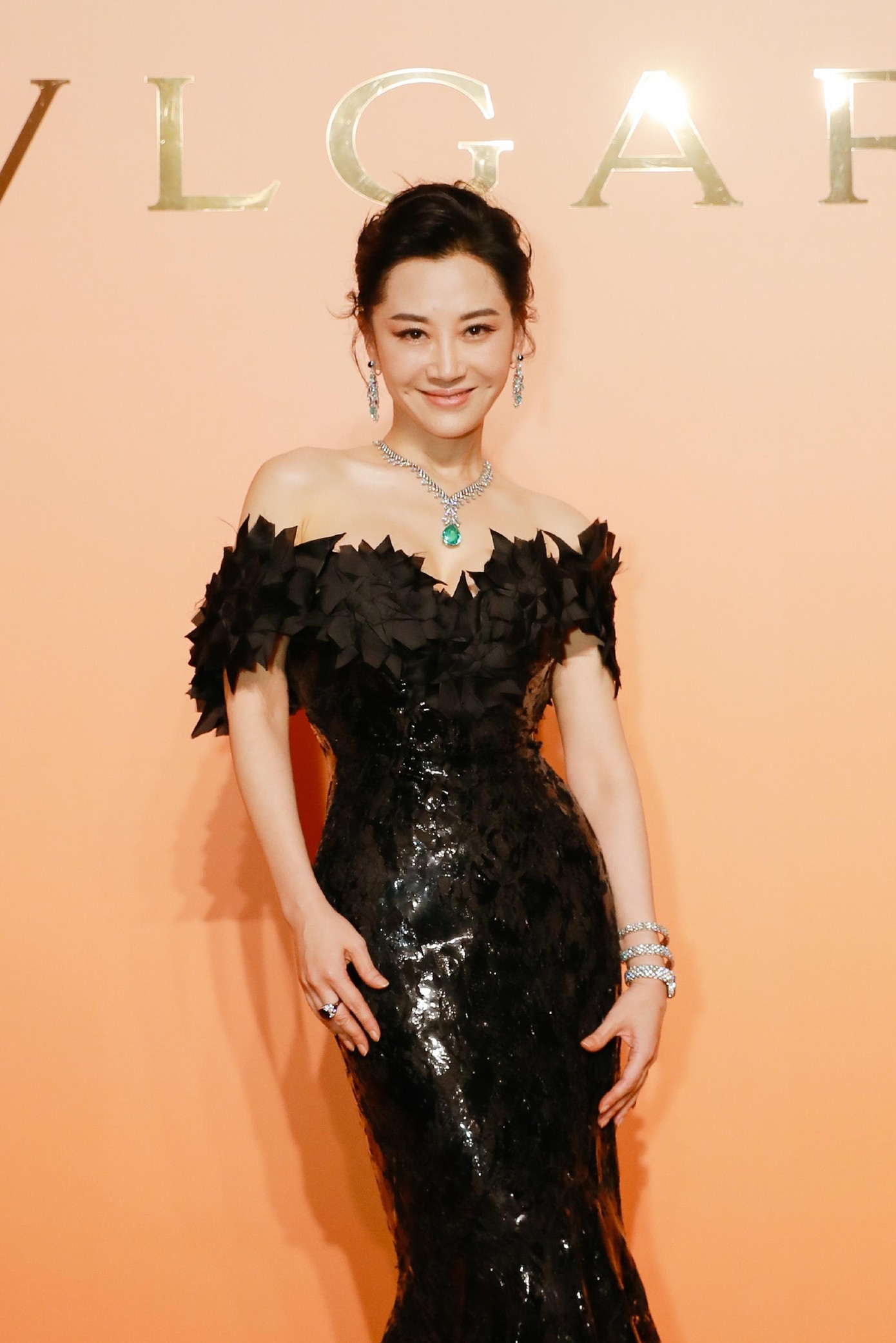 Người đẹp sinh năm 1969 mặc váy đen lấp lánh trễ vai ôm sát cơ thể, đeo trang sức Bvlgari, tóc búi cao và gương mặt trang điểm trong veo.