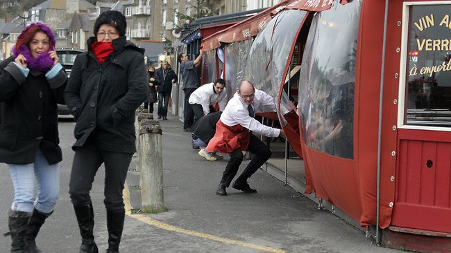 Nhân viên một cửa hàng cafe đóng cửa để bảo vệ khách khỏi gió lớn ở Cancale, Pháp