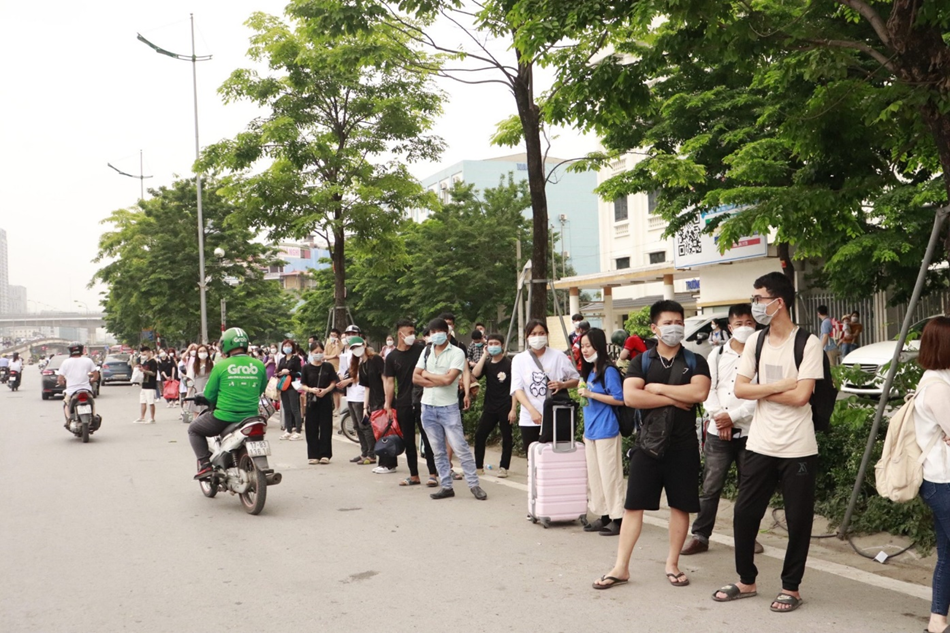Tại điểm trường Cao đẳng Thương mại và Du lịch Hà Nội (đường Phạm Văn Đồng) hàng trăm sinh viên với hành lý trên tay đứng vài tiếng đồng hồ đợi xe khách qua đón, vì sợ lỡ chuyến xe nhiều sinh viên đứng xuống cả vệ đường để quan sát. Ảnh: Linh Chi
