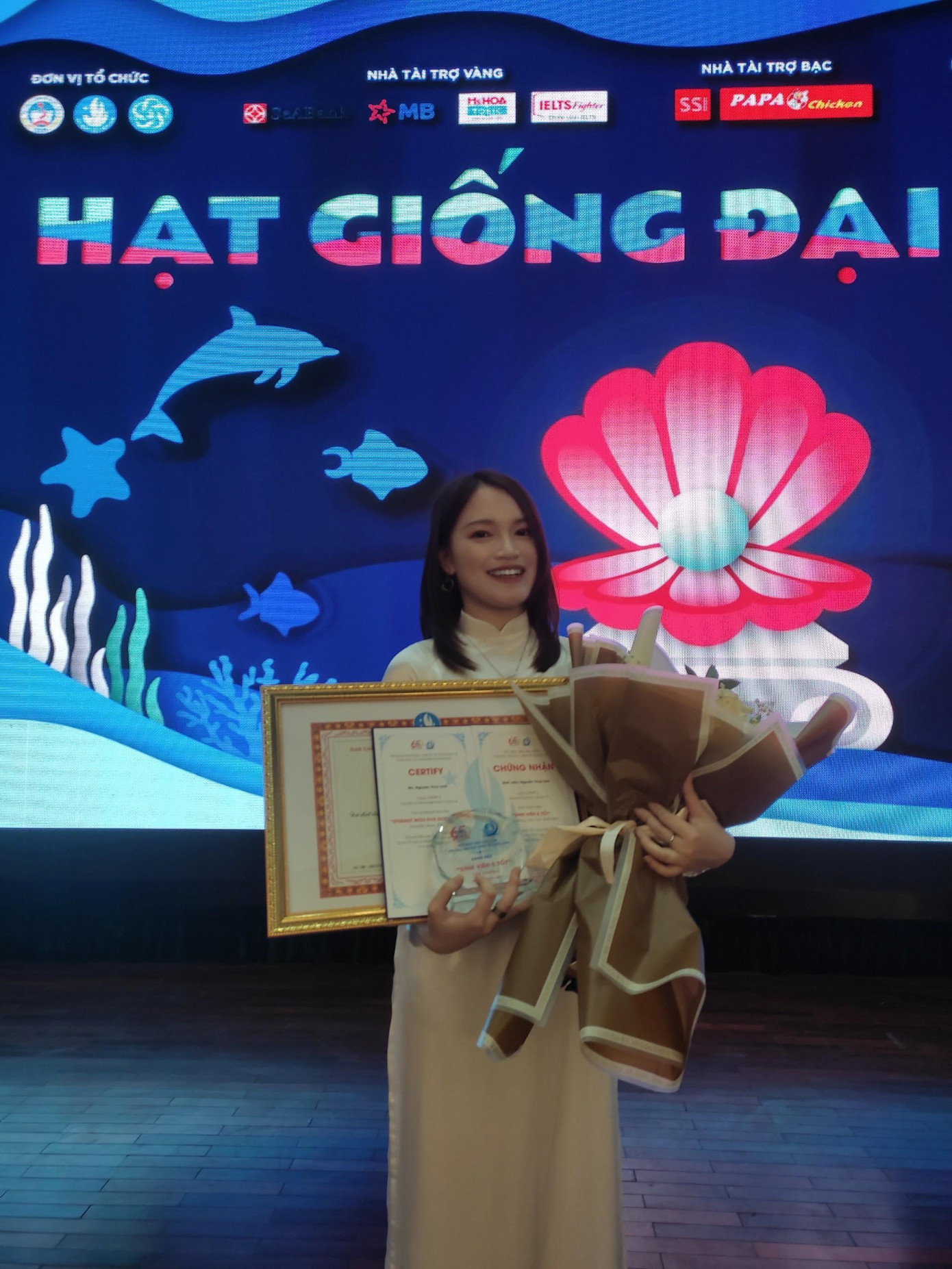 Cô nàng với tà áo dài trắng trên sân khấu nhận giải thưởng của đề tài nghiên cứu khoa học. Ảnh: NVCC