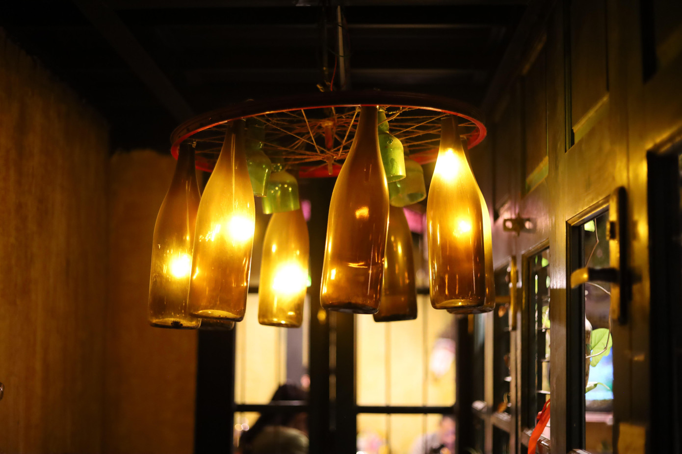 Chai thủy tinh và vành xe đạp cũ được "phù phép" thành chiếc đèn chùm rực rỡ.