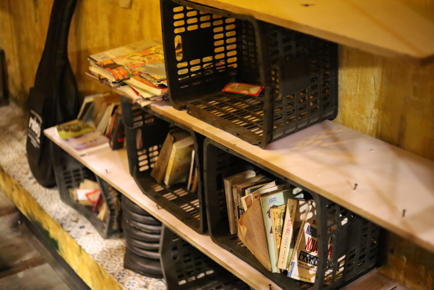 Rổ nhựa cũ được tận dụng làm giá sách.