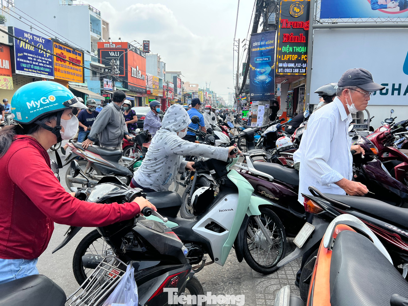 Nhiều khách hàng đứng tràn xuống lòng đường, đội nắng giữa trưa chờ gửi xe để vào cửa hàng chuẩn hóa thông tin thuê bao.