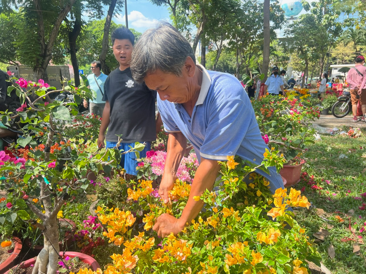 Lúc 12 giờ trưa, tiểu thương kinh doanh hoa Tết tại công viên 23/9 (quận 1) tự cắt bỏ hoa chứ không giảm giá, bán rẻ.