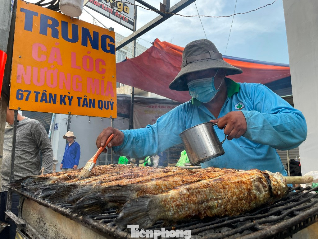 Ông Nguyễn Trung (59 tuổi) - chủ cửa hàng cá lóc nướng Trung cho biết, cách đó nhiều ngày đã đặt cá lóc tươi ngon nhất, trung bình mỗi con nặng 1-1,5kg. Từ mùng 9 Tết huy động 30 thành viên trong gia đình sơ chế và nướng cá. "Chúng tôi làm xuyên đêm để sáng mùng 10 có cá sớm để người dân kịp mua cúng Thần tài. Trung bình trong ngày này, chúng tôi bán khoảng 5.000 con cá lóc nướng (5 tấn)" - ông Trung nói.
