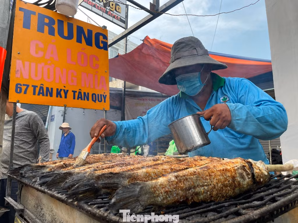 Ông Nguyễn Trung (59 tuổi) - chủ cửa hàng cá lóc nướng Trung cho biết, cách đó nhiều ngày đã đặt cá lóc tươi ngon nhất, trung bình mỗi con nặng 1-1,5kg. Từ mùng 9 Tết huy động 30 thành viên trong gia đình sơ chế và nướng cá. "Chúng tôi làm xuyên đêm để sáng mùng 10 có cá sớm để người dân kịp mua cúng Thần tài. Trung bình trong ngày này, chúng tôi bán khoảng 5.000 con cá lóc nướng (5 tấn)" - ông Trung nói.