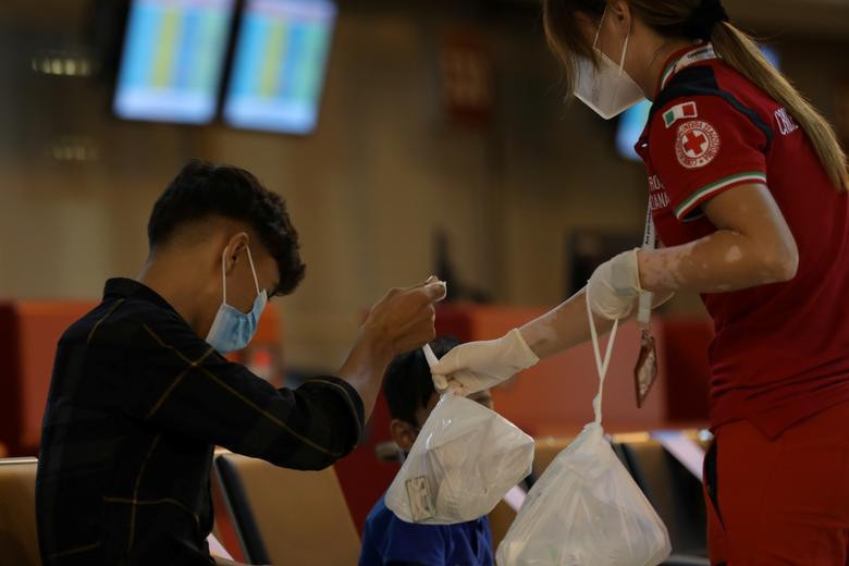 Một cậu bé người Afghanistan nhận thực phẩm từ một thành viên Hội Chữ thập đỏ sau khi đáp xuống sân bay Fiumicino (Rome, Ý) ngày 16/8.