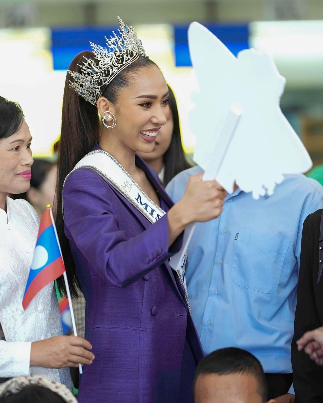 Papao Phaimany Lathsabunthao diện vest xanh, khoe eo thon. Nhiều khán giả cũng ra sân bay để tiễn người đẹp.