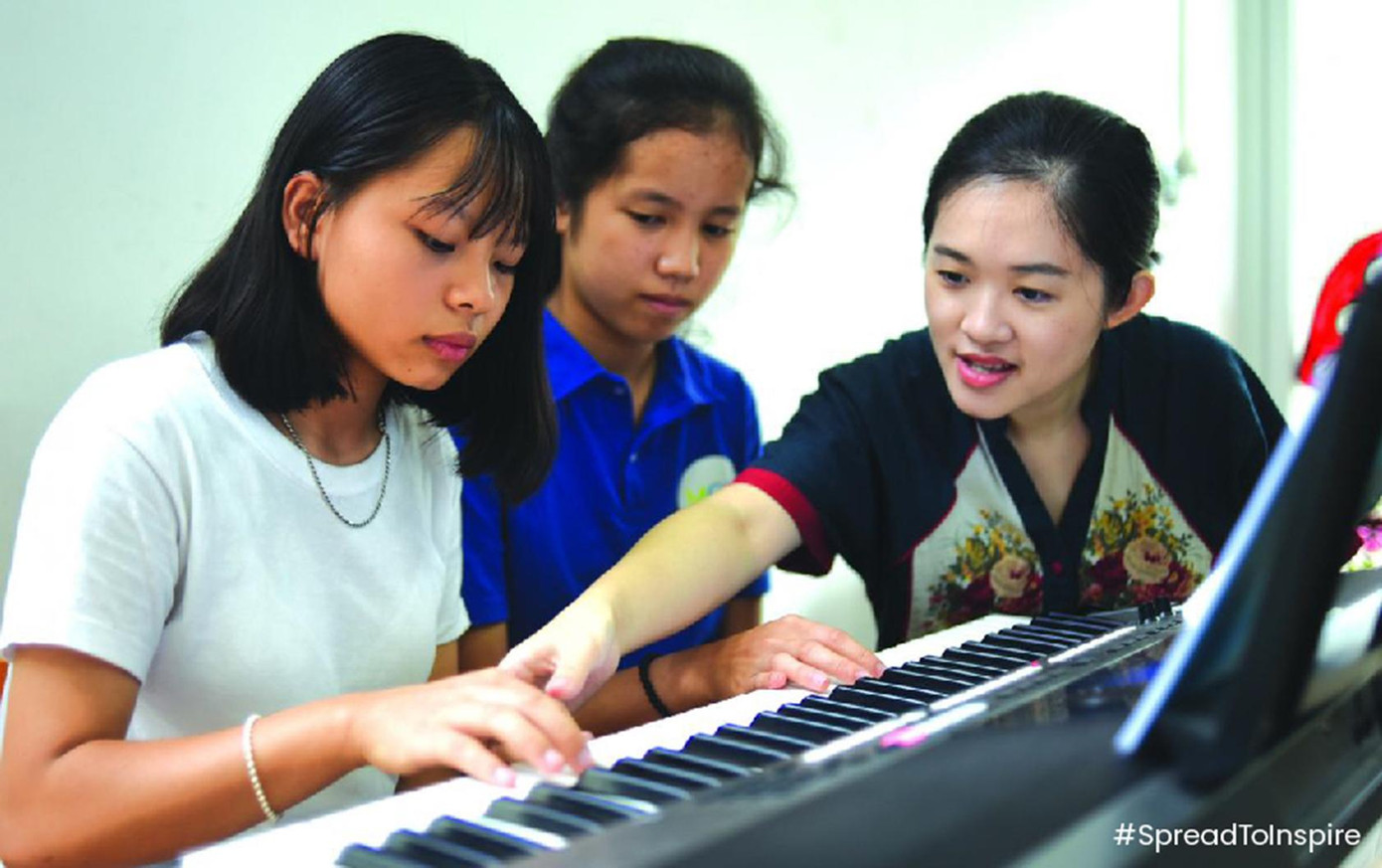 Trang Trịnh hướng dẫn các em thuộc Dàn Hợp xướng và Giao hưởng Kỳ diệu (Miracle Choir &amp; Orchestra) cách chơi đàn. Ảnh: vietnamnows.