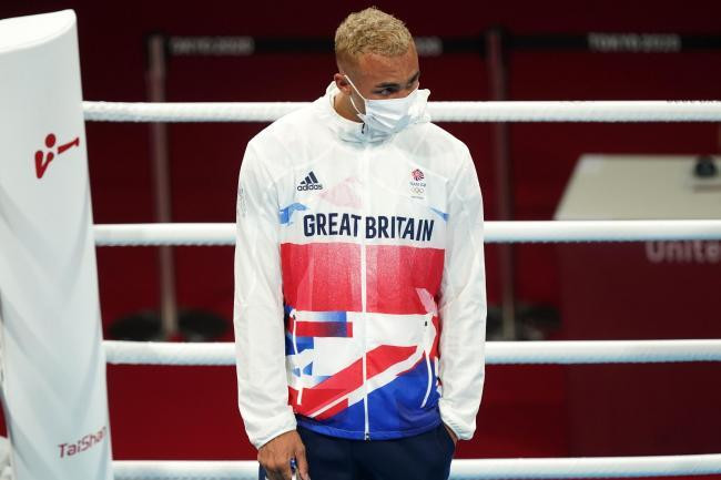 Whittaker bỏ huy chương vào túi quần khi lên nhận giải