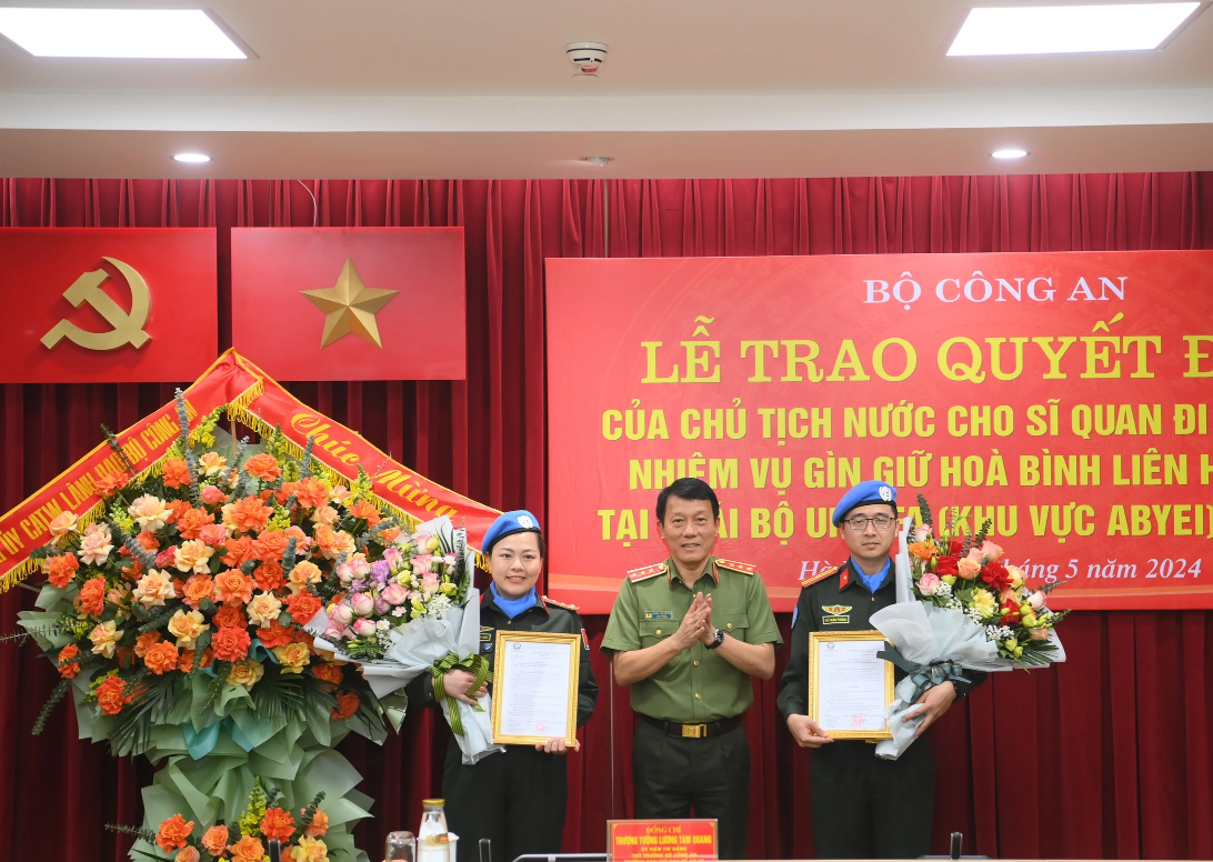 Thượng tướng Lương Tam Quang, Thứ trưởng Bộ Công an, trao quyết định và tặng hoa 2 sĩ quan tại buổi lễ. Ảnh: A.C